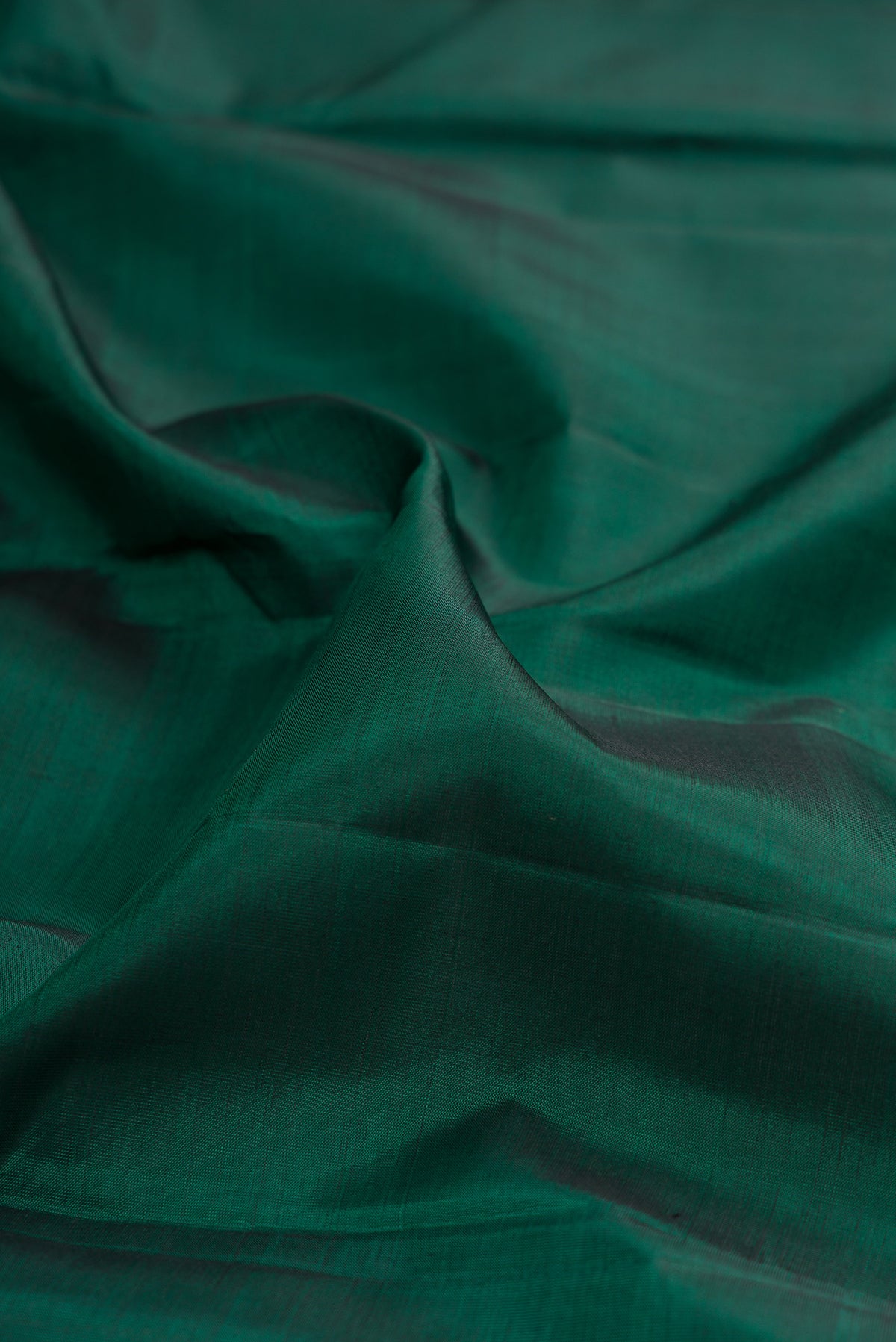 Close up of Bottle Green Kanjivaram Silk Saree with Plain Body and Zari Border.  displaying folds