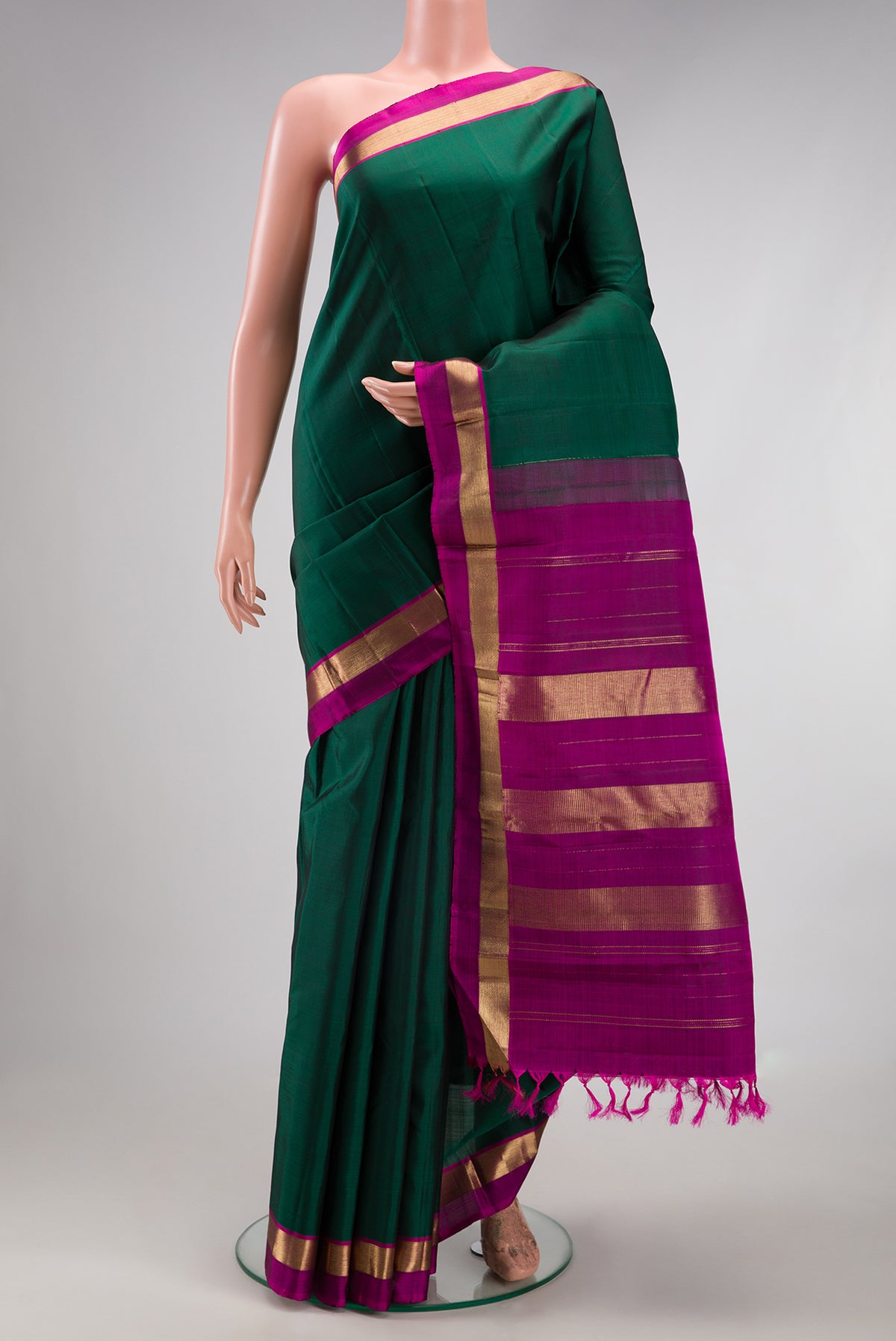 Bottle Green Kanjivaram Silk Saree with Plain Body and Zari Border.  displayed on a mannequin