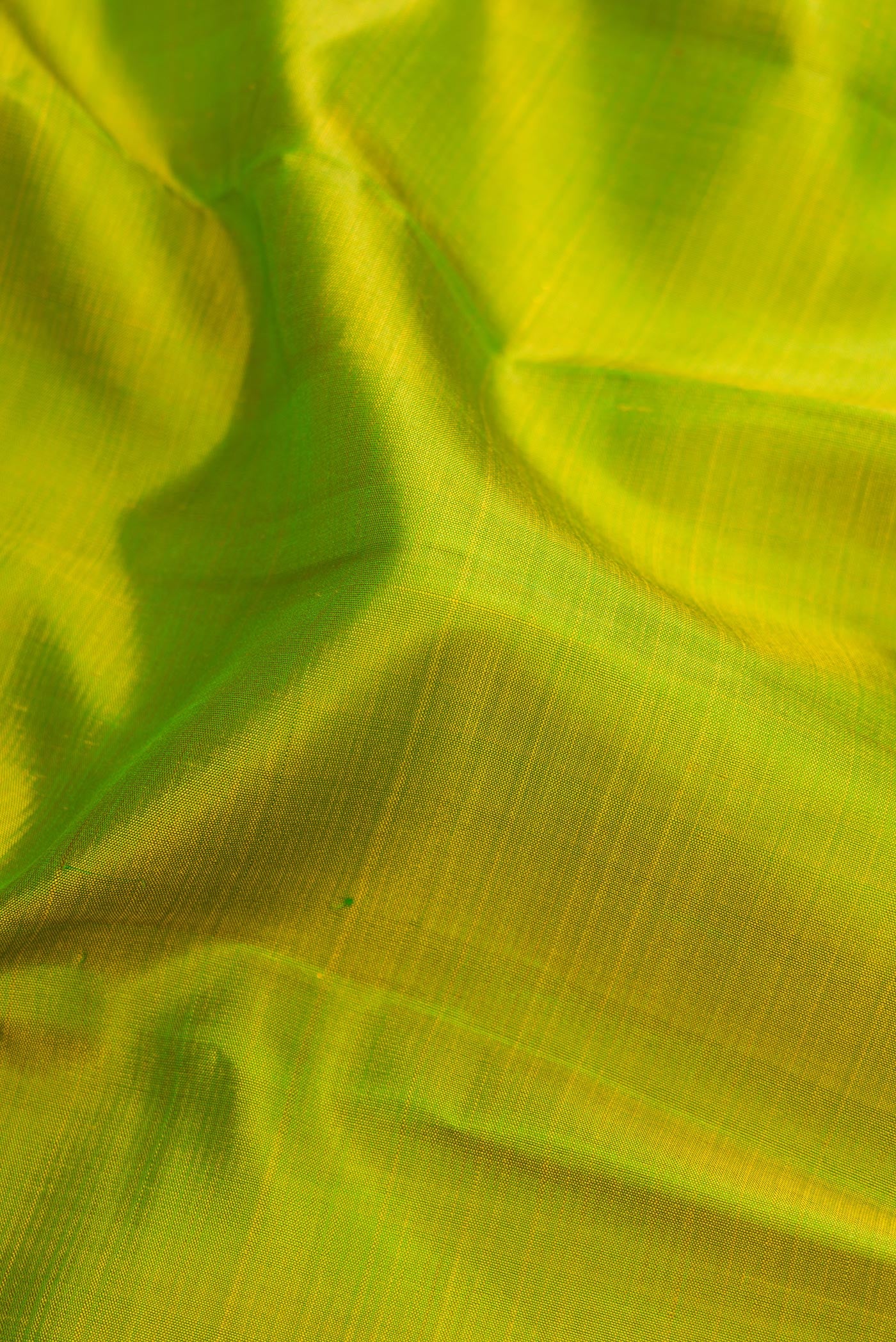 Close up of Parrot Green Kanjivaram Silk Saree with Plain Body and Zari Border.  displaying folds