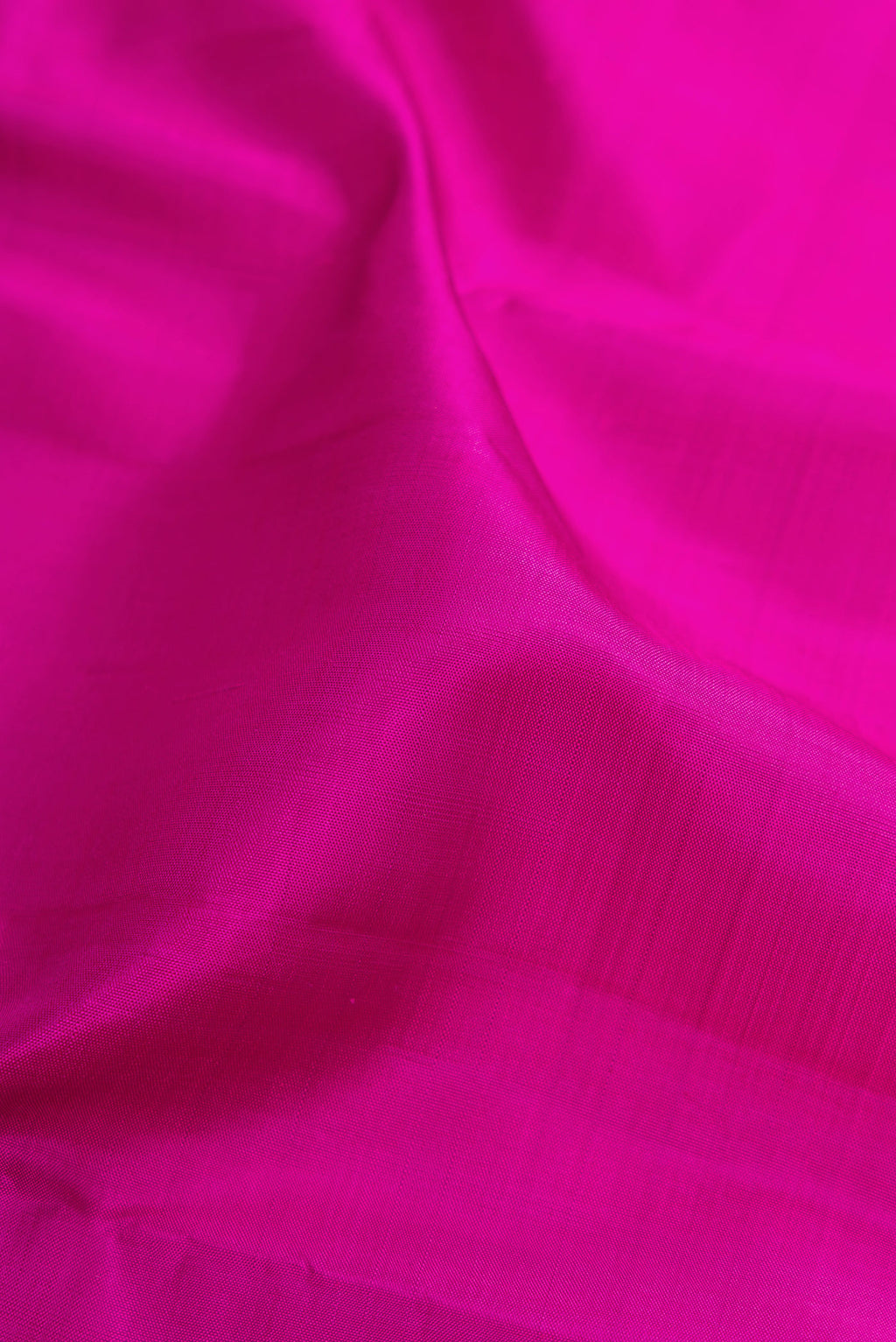 Close up of Magenta Kanjivaram Silk Saree with Plain Body and Zari Border.  displaying folds