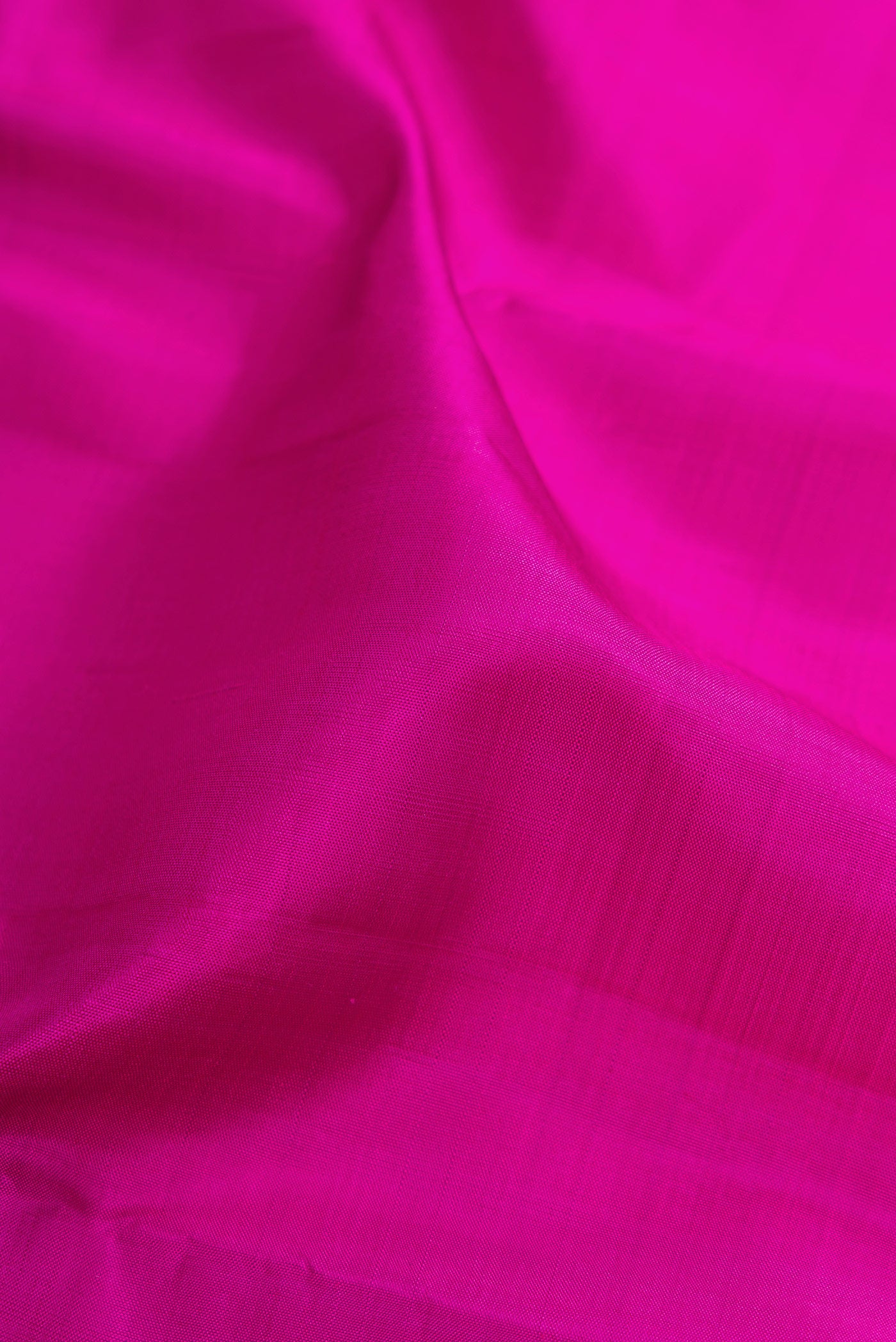 Close up of Magenta Kanjivaram Silk Saree with Plain Body and Zari Border.  displaying folds