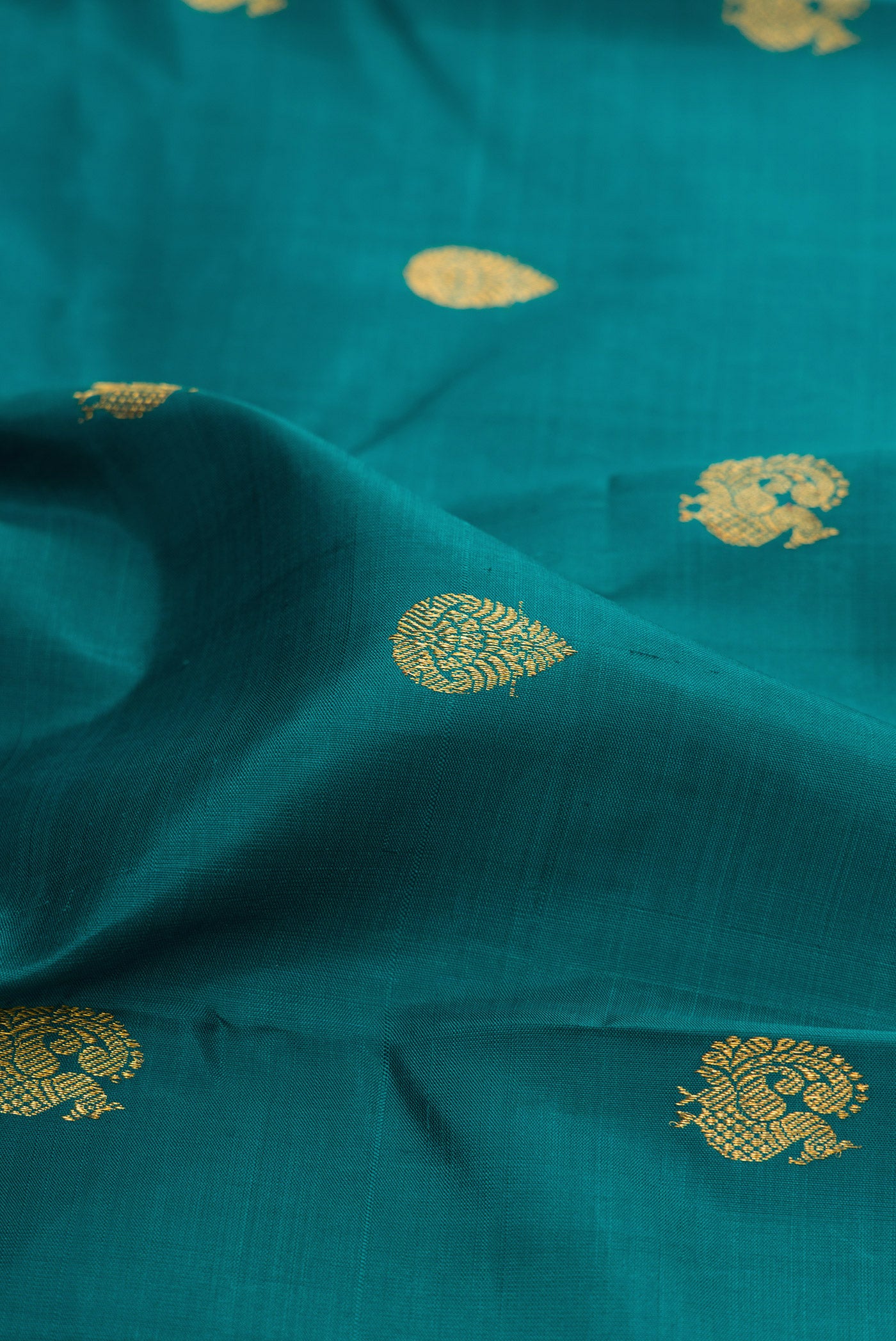 Close up of Peacock Blue Kanchipuram Silk Saree with Zari Butta on the body and Zari Border.  displaying folds