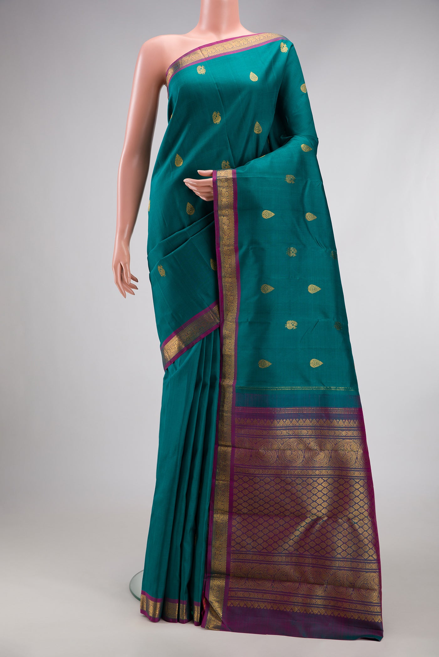 Peacock Blue Kanchipuram Silk Saree with Zari Butta on the body and Zari Border.  displayed on a mannequin