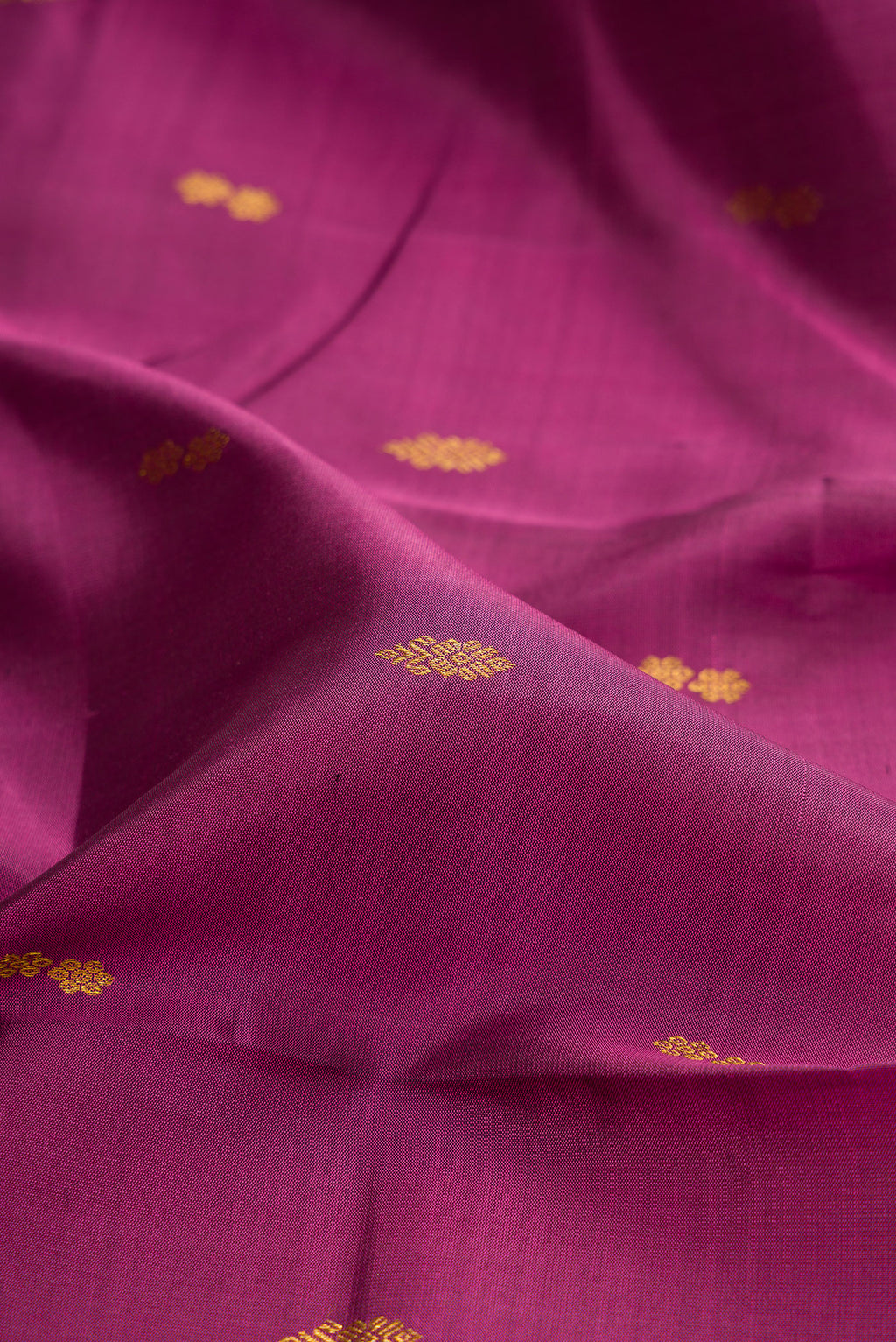 Close up of Magenta Kanchipuram Silk Saree with Zari Butta on the body and Zari Border.  displaying folds