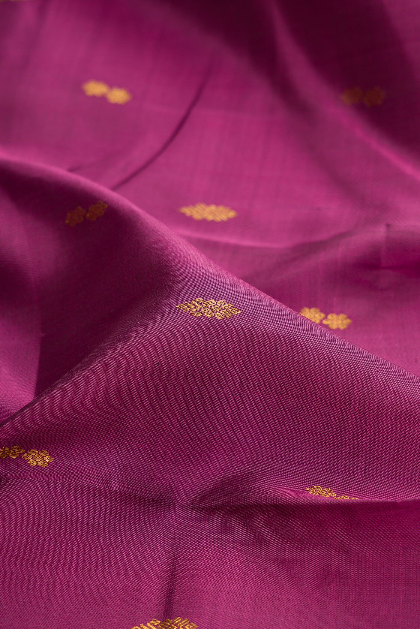 Close up of Magenta Kanchipuram Silk Saree with Zari Butta on the body and Zari Border.  displaying folds