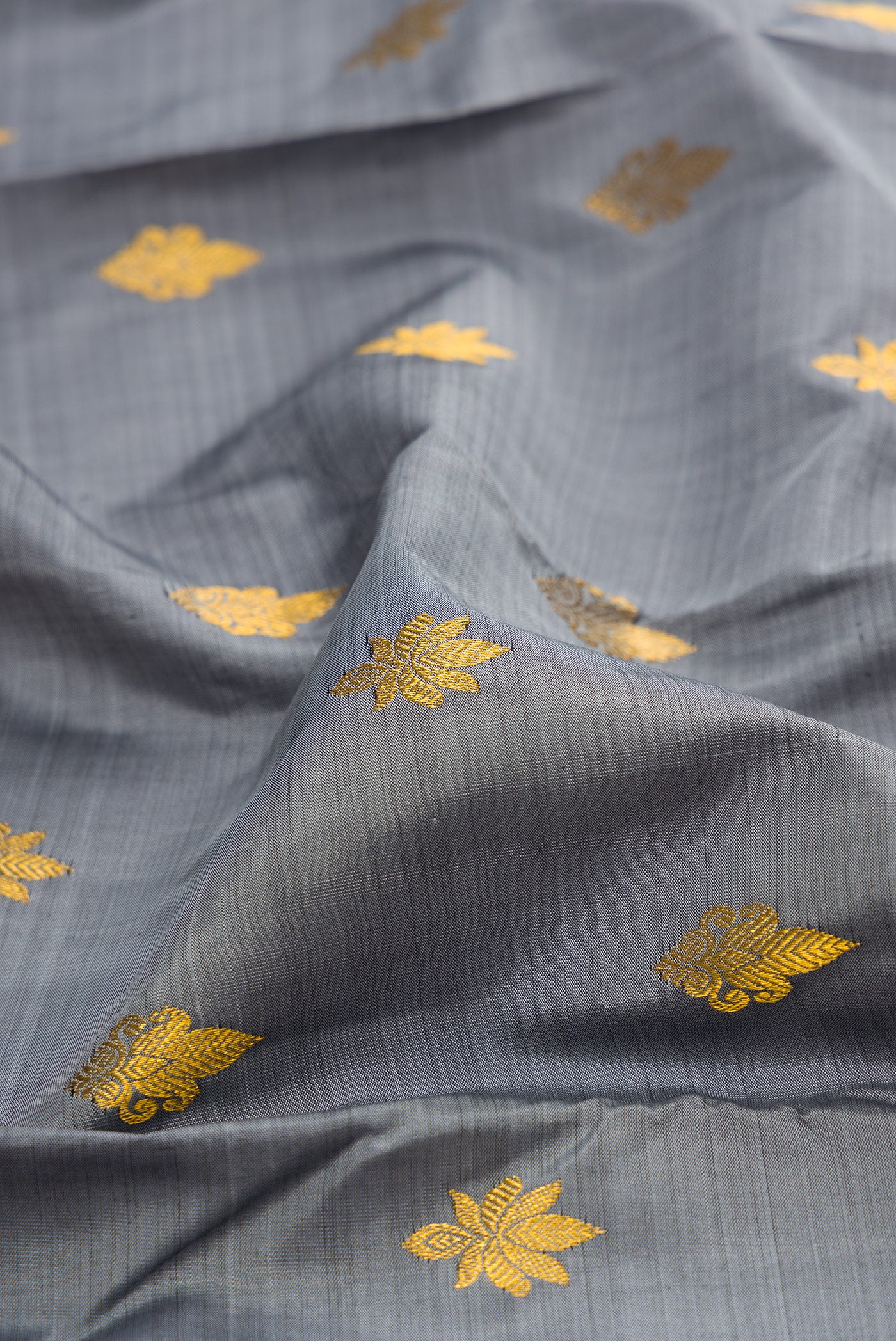 Close up of Grey Kanchipuram Silk Saree with Zari Butta on the body and Zari Border.  displaying folds