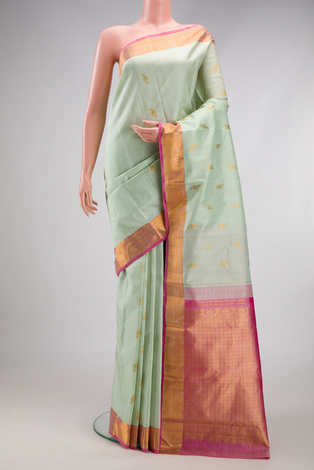 Light Green Kanchipuram Silk Saree with Zari Butta on the body and Zari Border.  displayed on a mannequin