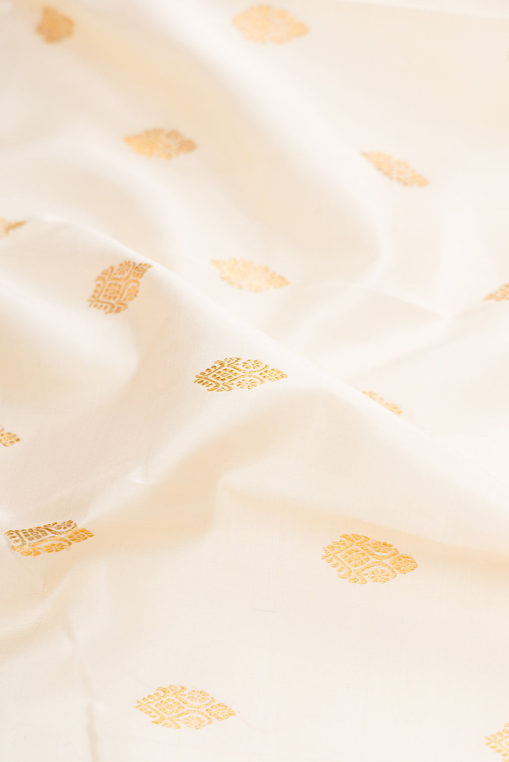 Close up of Off White Kanjivaram Silk Saree with Zari Butta on the body and Zari Border.  displaying folds