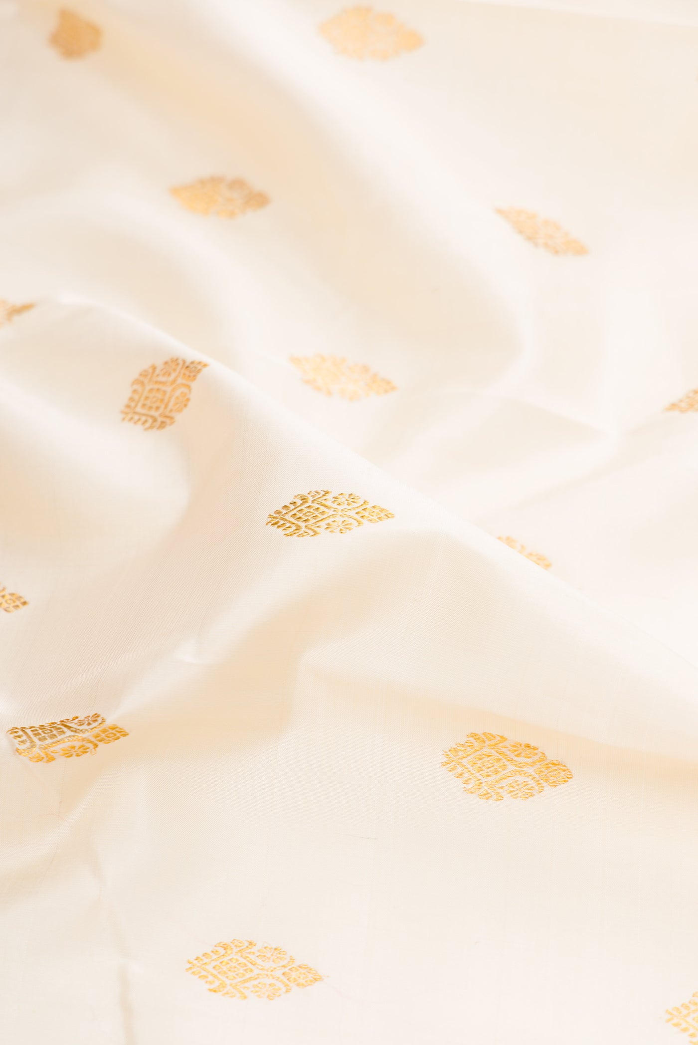 Close up of Off White Kanjivaram Silk Saree with Zari Butta on the body and Zari Border.  displaying folds