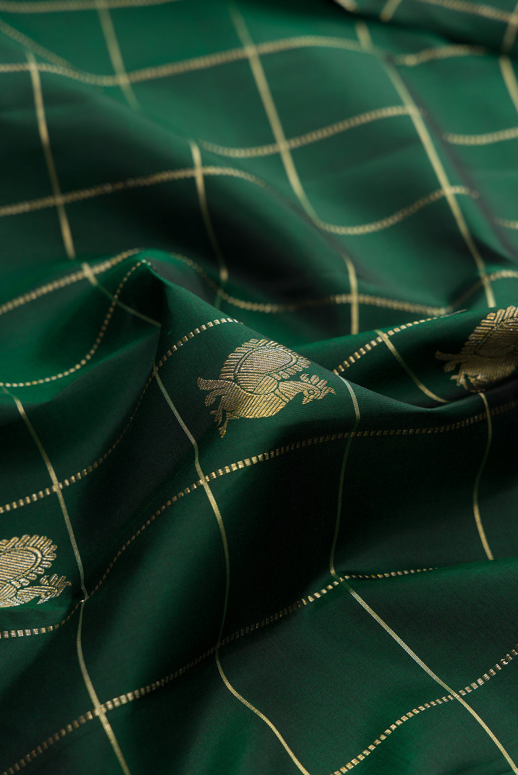 Close up of Pure Silk Bottle Green Kanchipuram Saree with Checked design on the body and Plain Border.  displaying folds