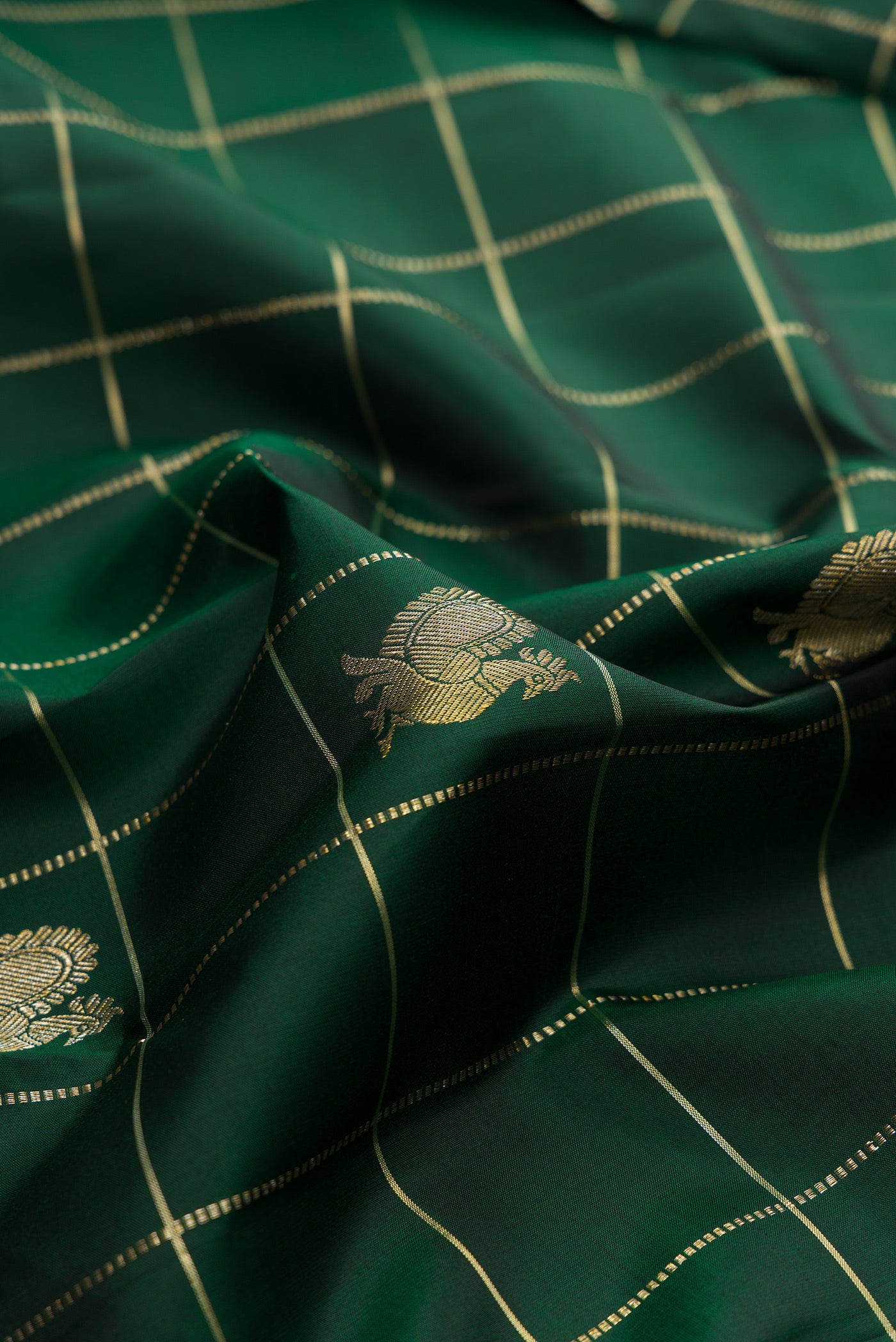 Close up of Pure Silk Bottle Green Kanchipuram Saree with Checked design on the body and Plain Border.  displaying folds