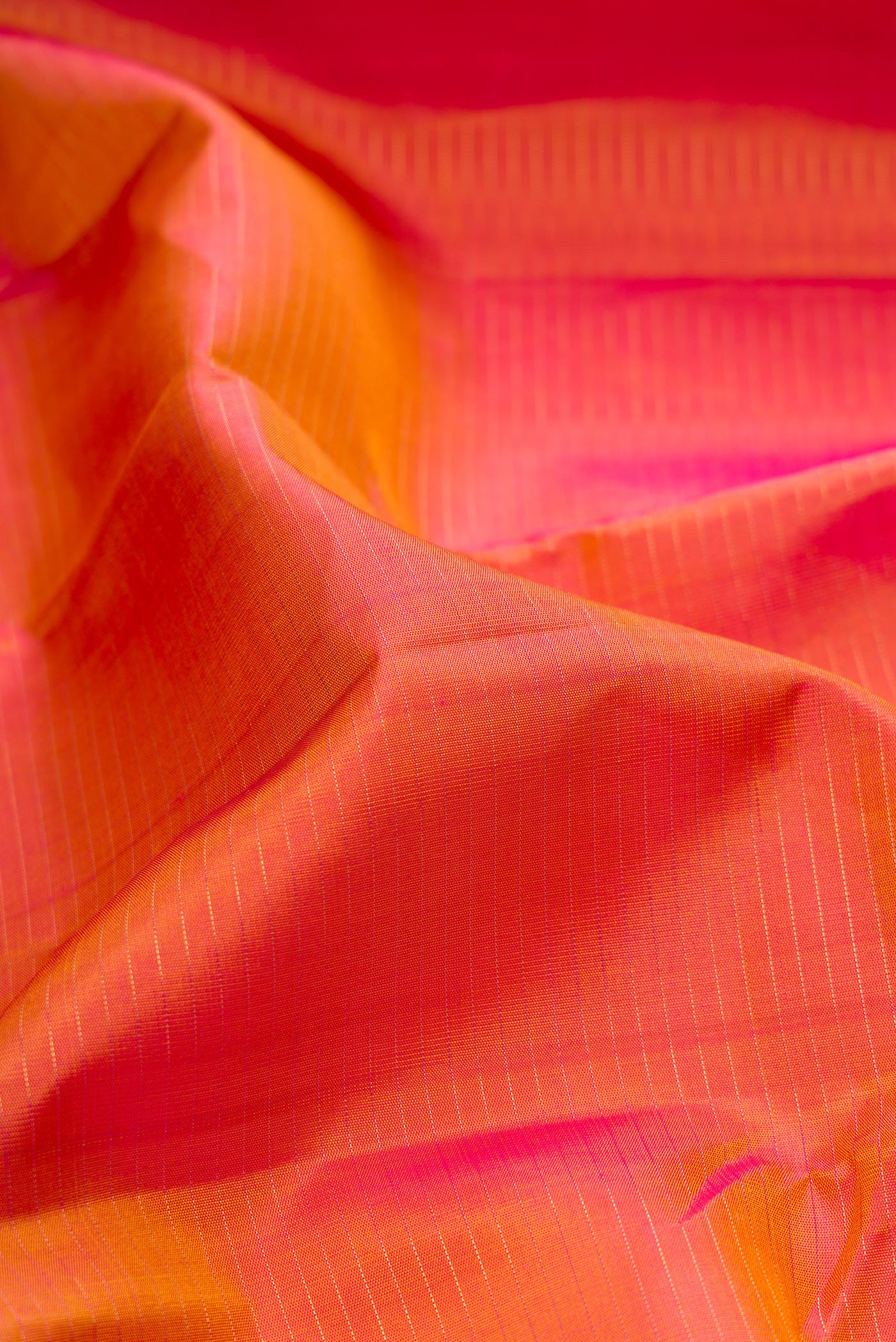 Close up of Orange Kanjivaram Silk Saree with Stripes on the body and Ganga Jamuna Border.  displaying folds