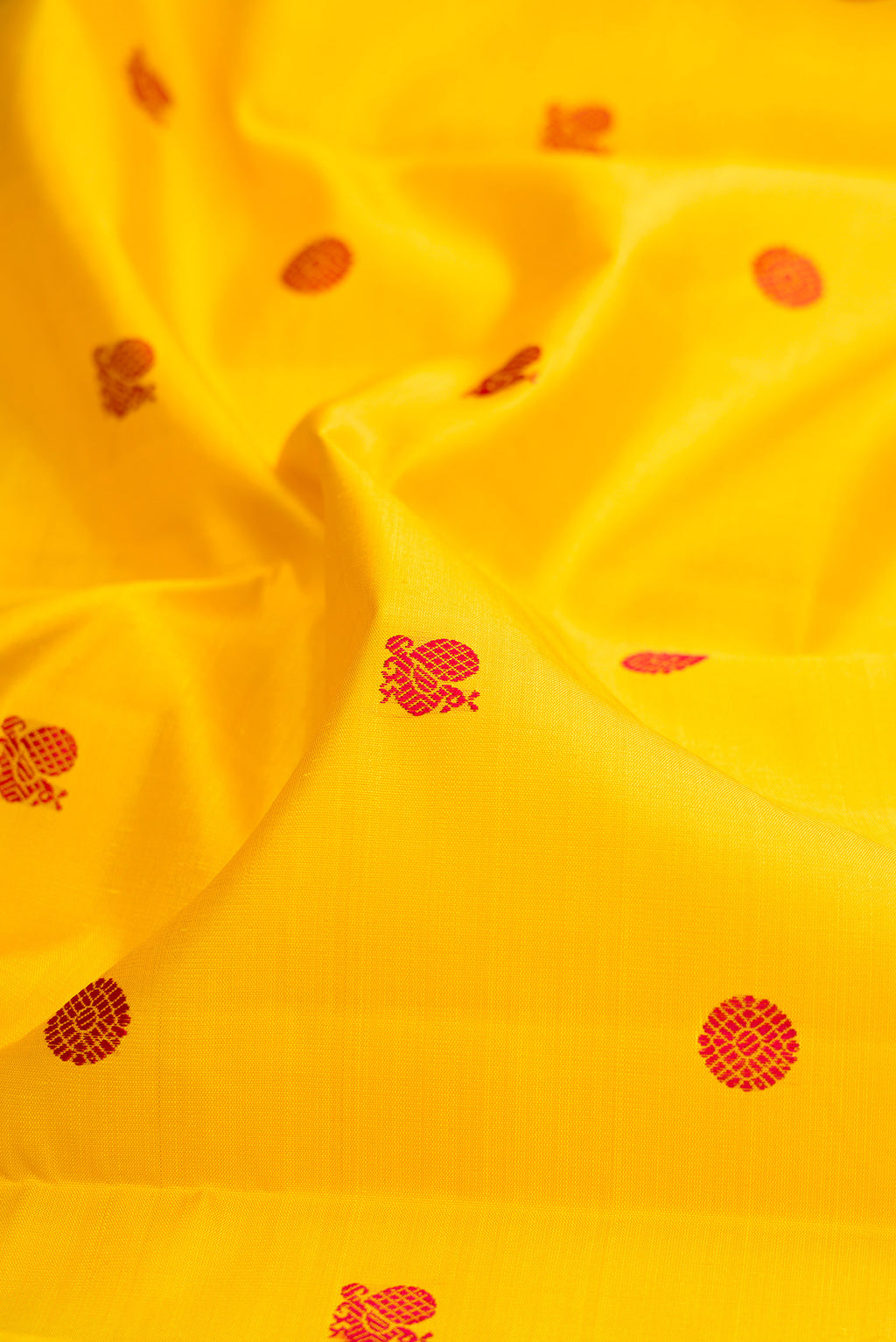 Close up of Yellow Kanjivaram Silk Saree with Thread Butta on the body and Zari Border.  displaying folds