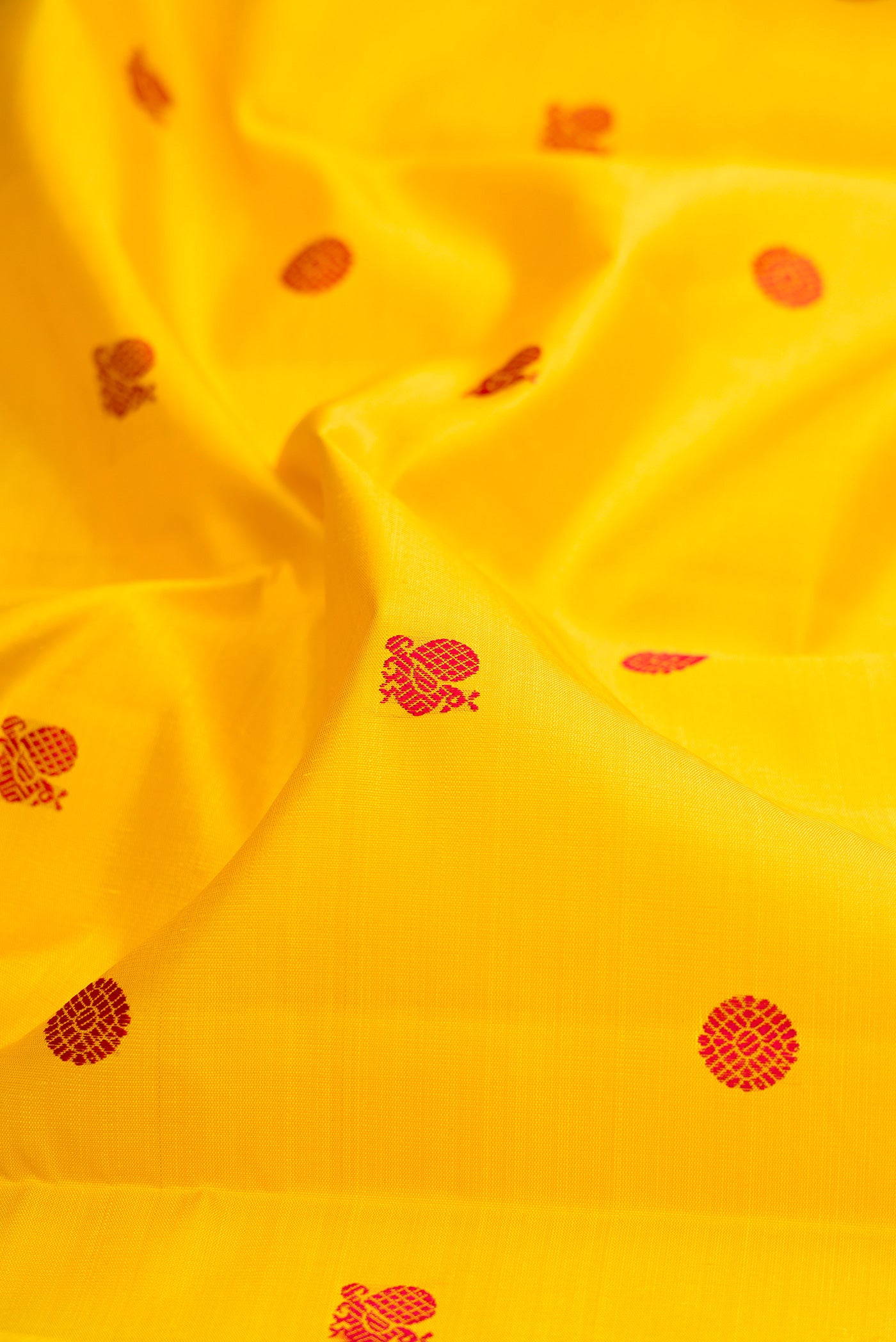 Close up of Yellow Kanjivaram Silk Saree with Thread Butta on the body and Zari Border.  displaying folds
