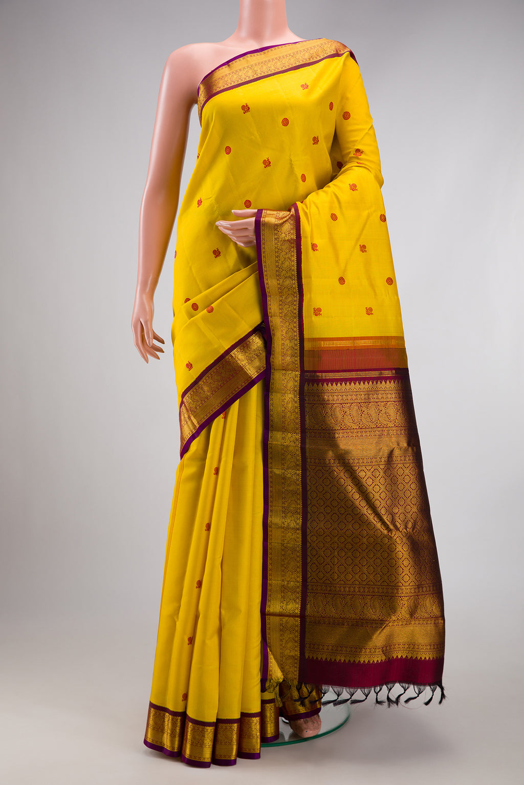 Yellow Kanjivaram Silk Saree with Thread Butta on the body and Zari Border.  displayed on a mannequin