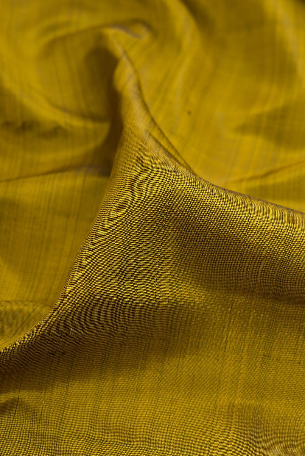 Close up of Mehandi Green Kanjivaram Silk Saree with Plain Body and Zari Border.  displaying folds