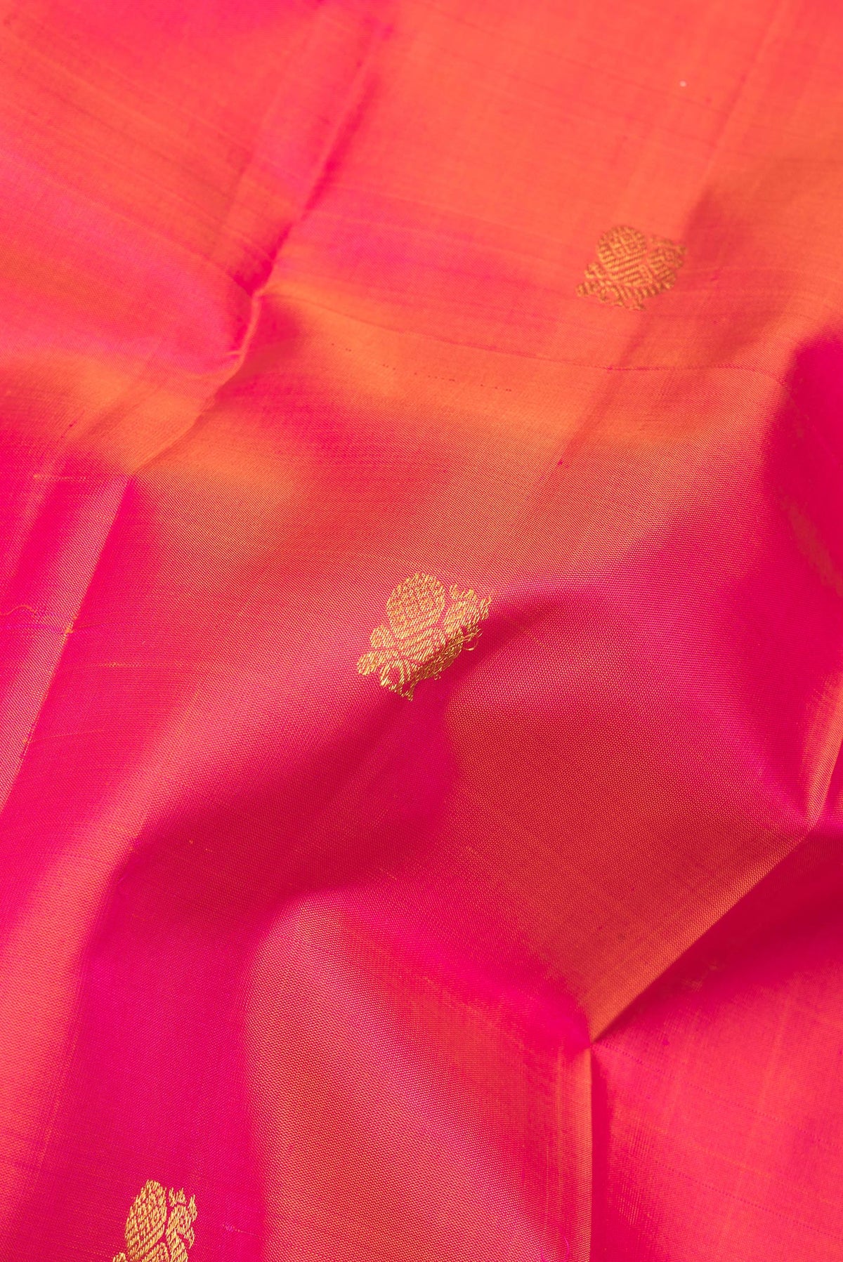 Close up of Pure Silk Coral Dual Tone Kanchipuram Saree with Zari Butta on the body and Without Border.  displaying folds