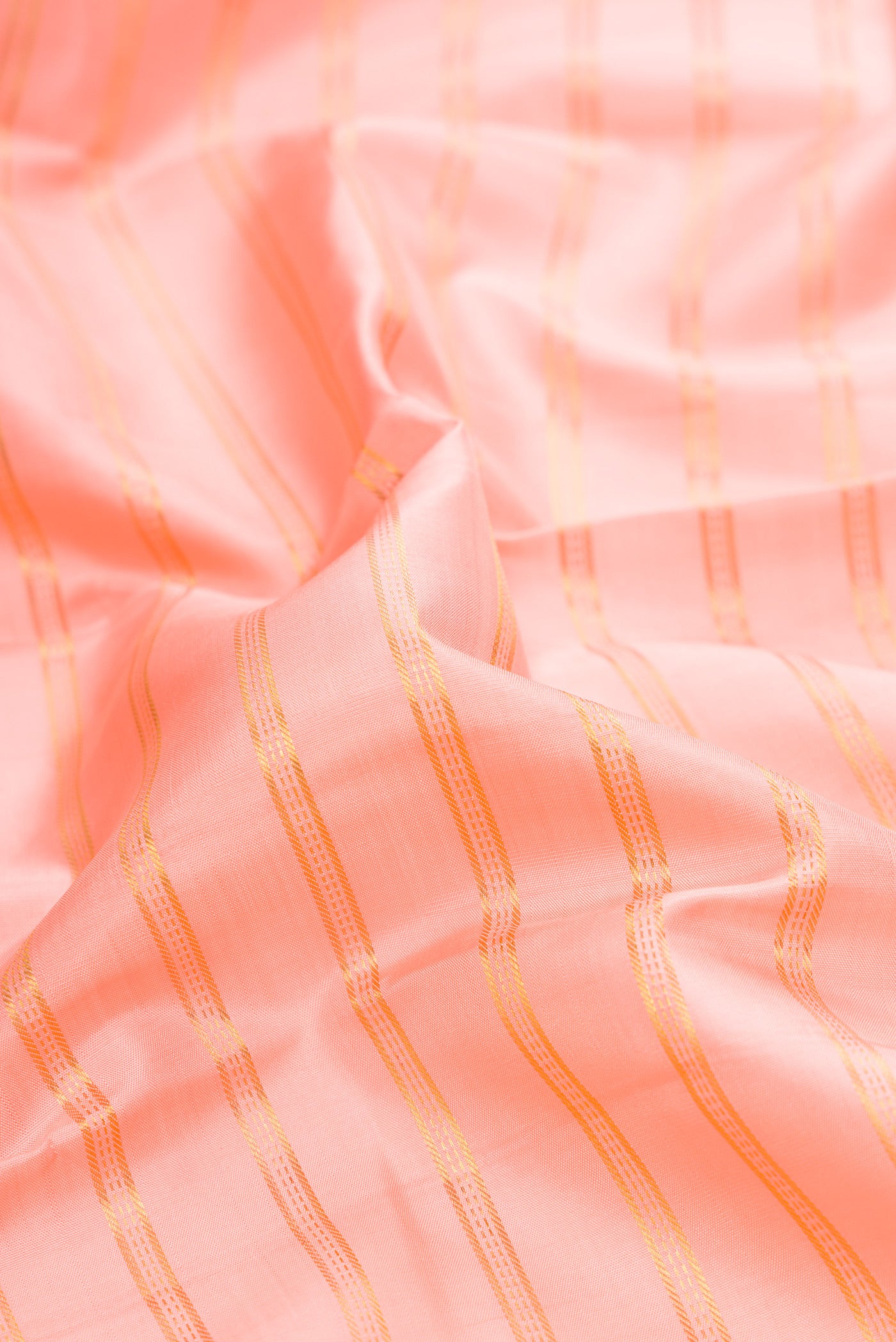 Close up of Peach Kanjivaram Silk Saree with Stripes on the body and Zari Border.  displaying folds