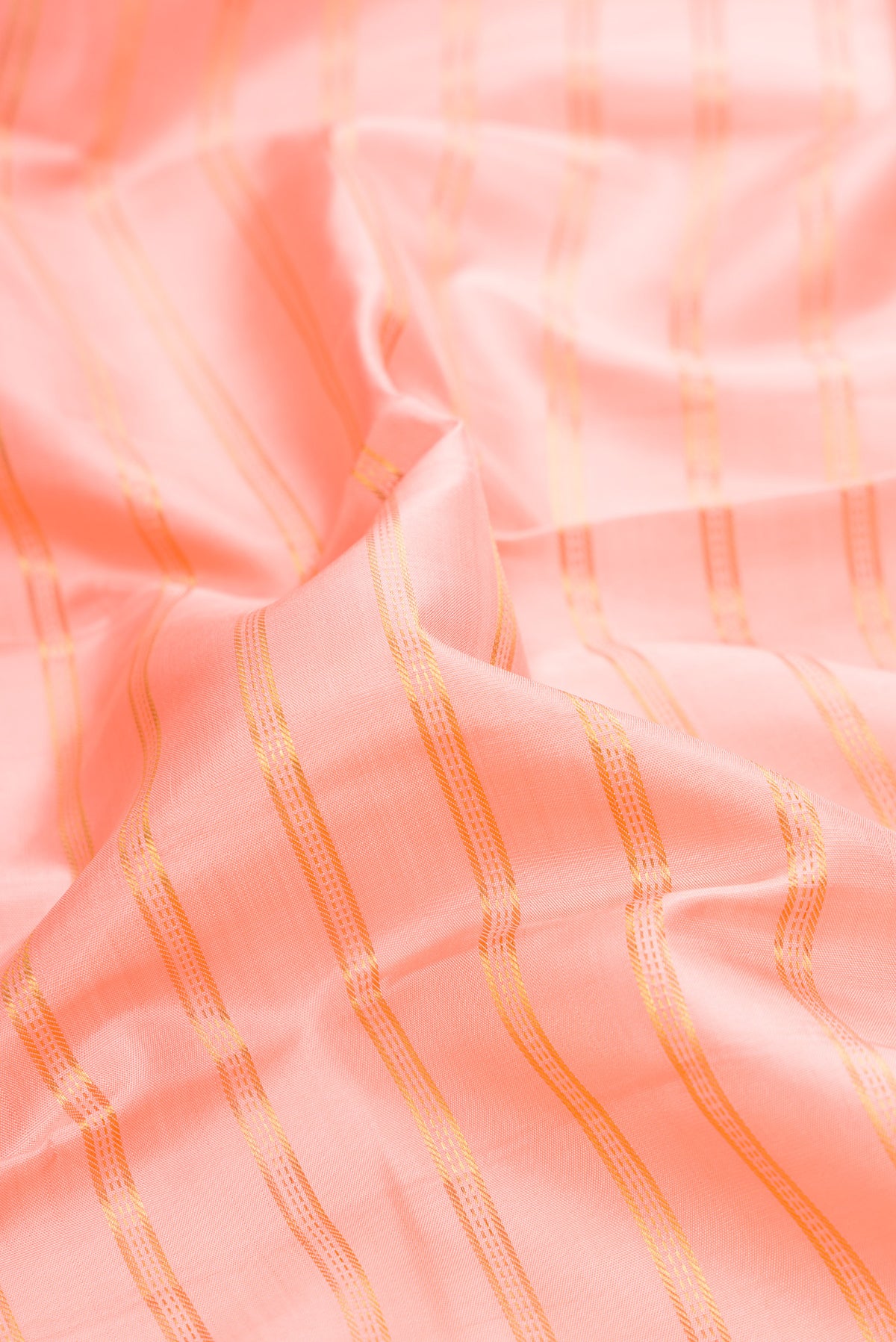Close up of Peach Kanjivaram Silk Saree with Stripes on the body and Zari Border.  displaying folds