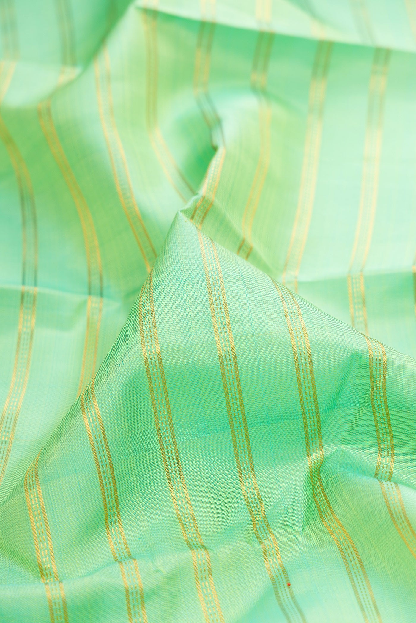 Close up of Pista Green Kanjivaram Silk Saree with Stripes on the body and Zari Border.  displaying folds