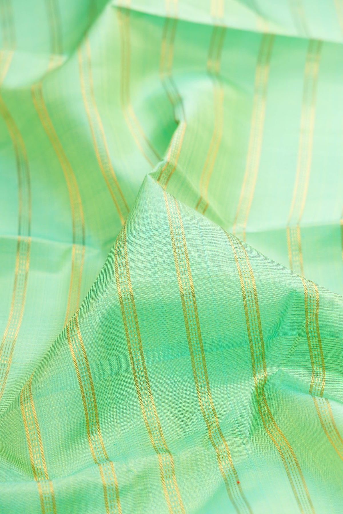 Close up of Pista Green Kanjivaram Silk Saree with Stripes on the body and Zari Border.  displaying folds