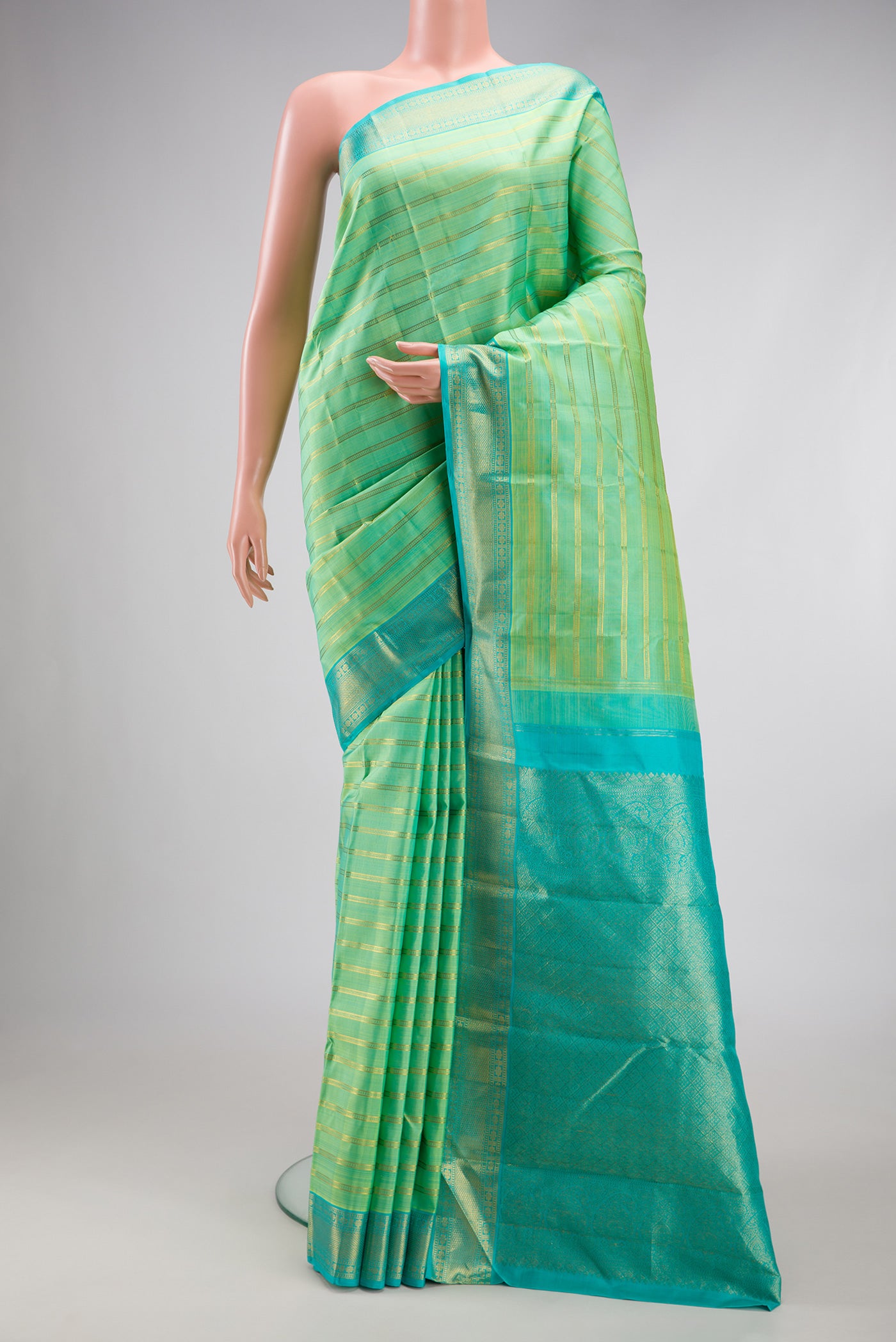 Pista Green Kanjivaram Silk Saree with Stripes on the body and Zari Border.  displayed on a mannequin