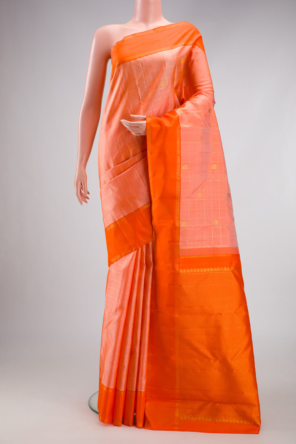 Golden Peach Kanchipuram Silk Saree with Checked design on the body and Plain Border.  displayed on a mannequin