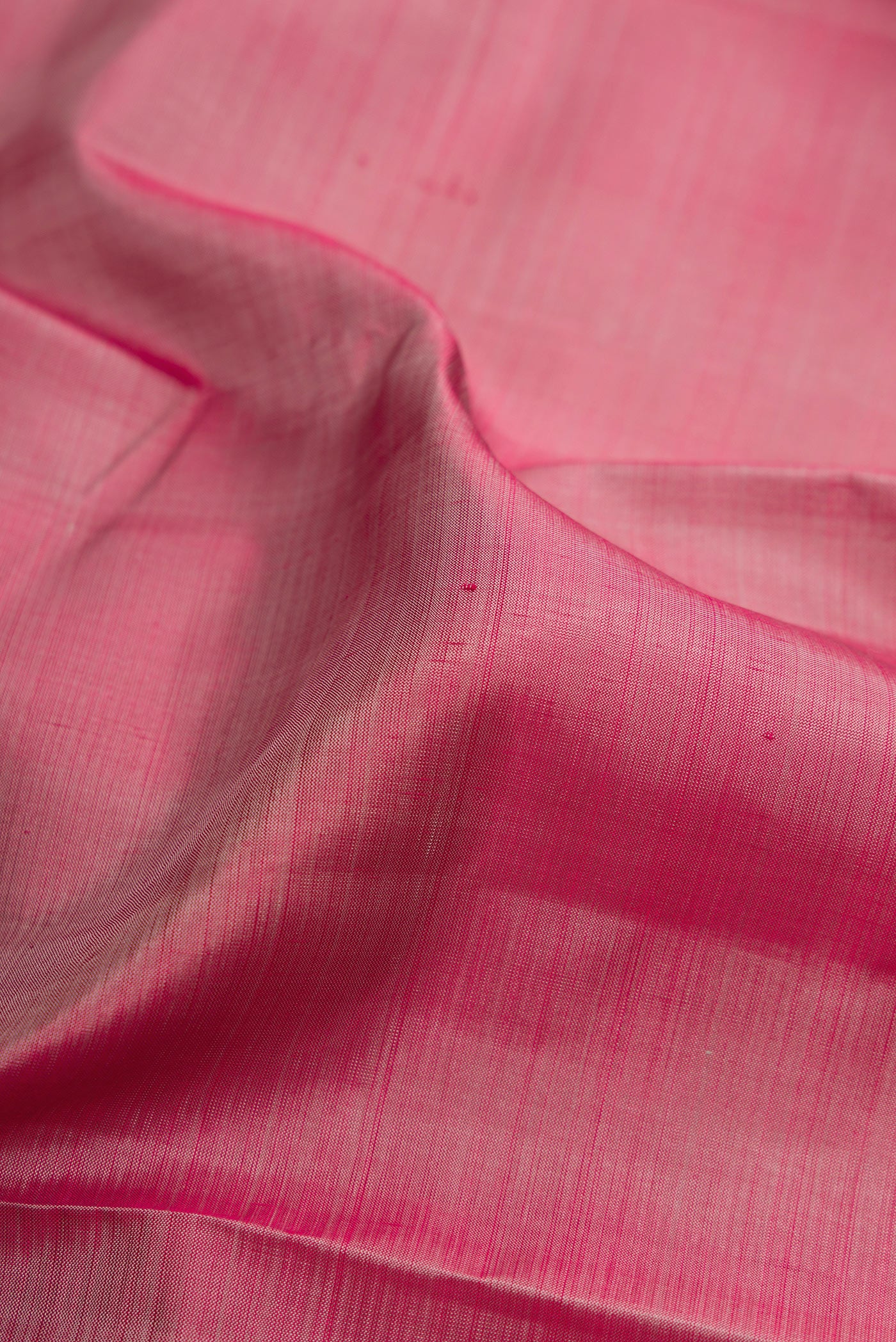 Close up of Rose Gold Kanjivaram Silk Saree with Plain Body and Zari Border.  displaying folds