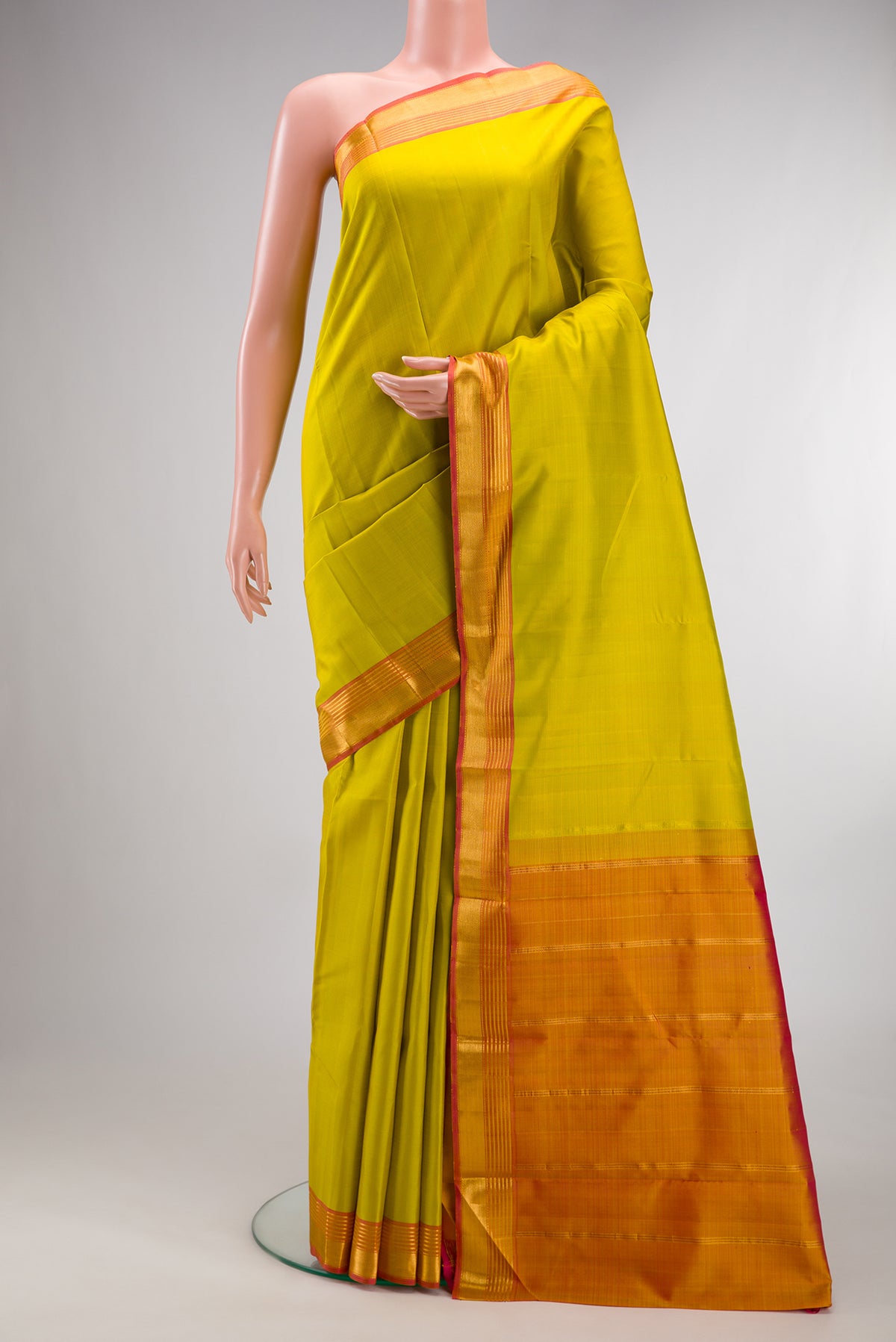 Pure Silk Parrot Green Kanjivaram Saree with Plain Body and Zari Border.  displayed on a mannequin