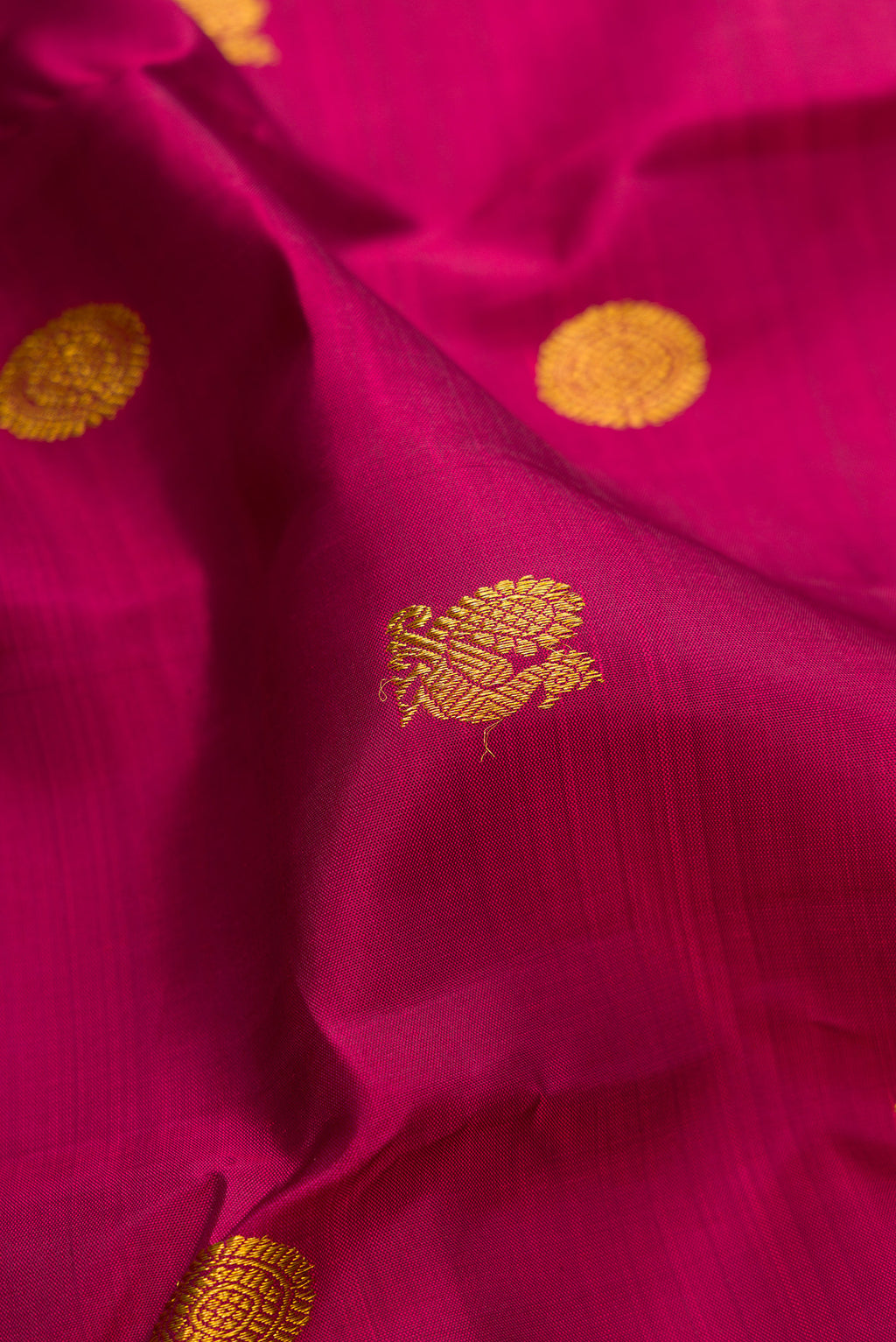 Close up of Magenta Kanjivaram Silk Saree with Zari Butta on the body and Zari Border.  displaying folds