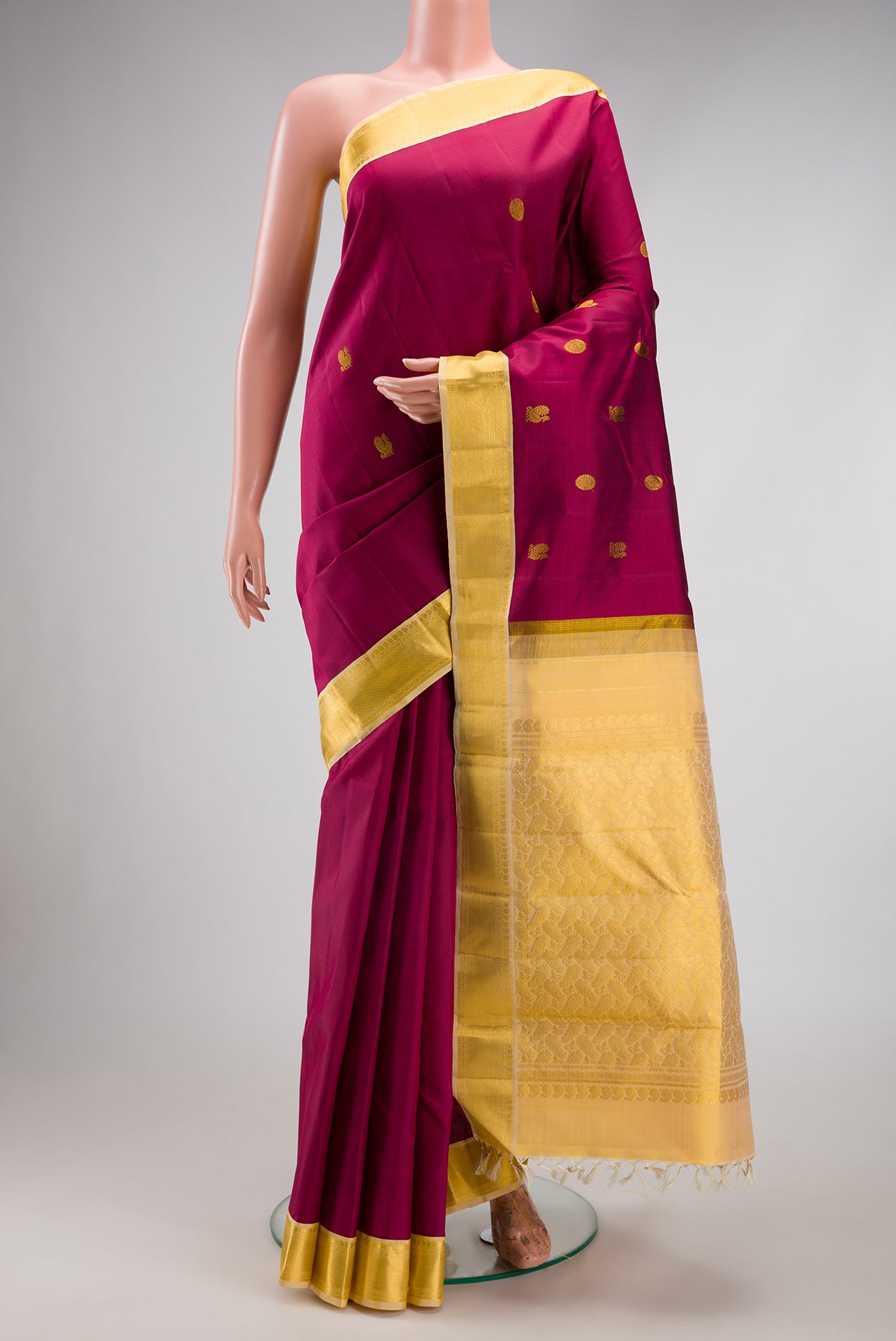 Magenta Kanjivaram Silk Saree with Zari Butta on the body and Zari Border.  displayed on a mannequin