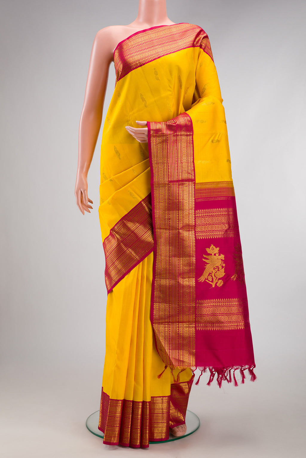 Yellow Kanjivaram Silk Saree with Zari Butta on the body and Zari Border.  displayed on a mannequin