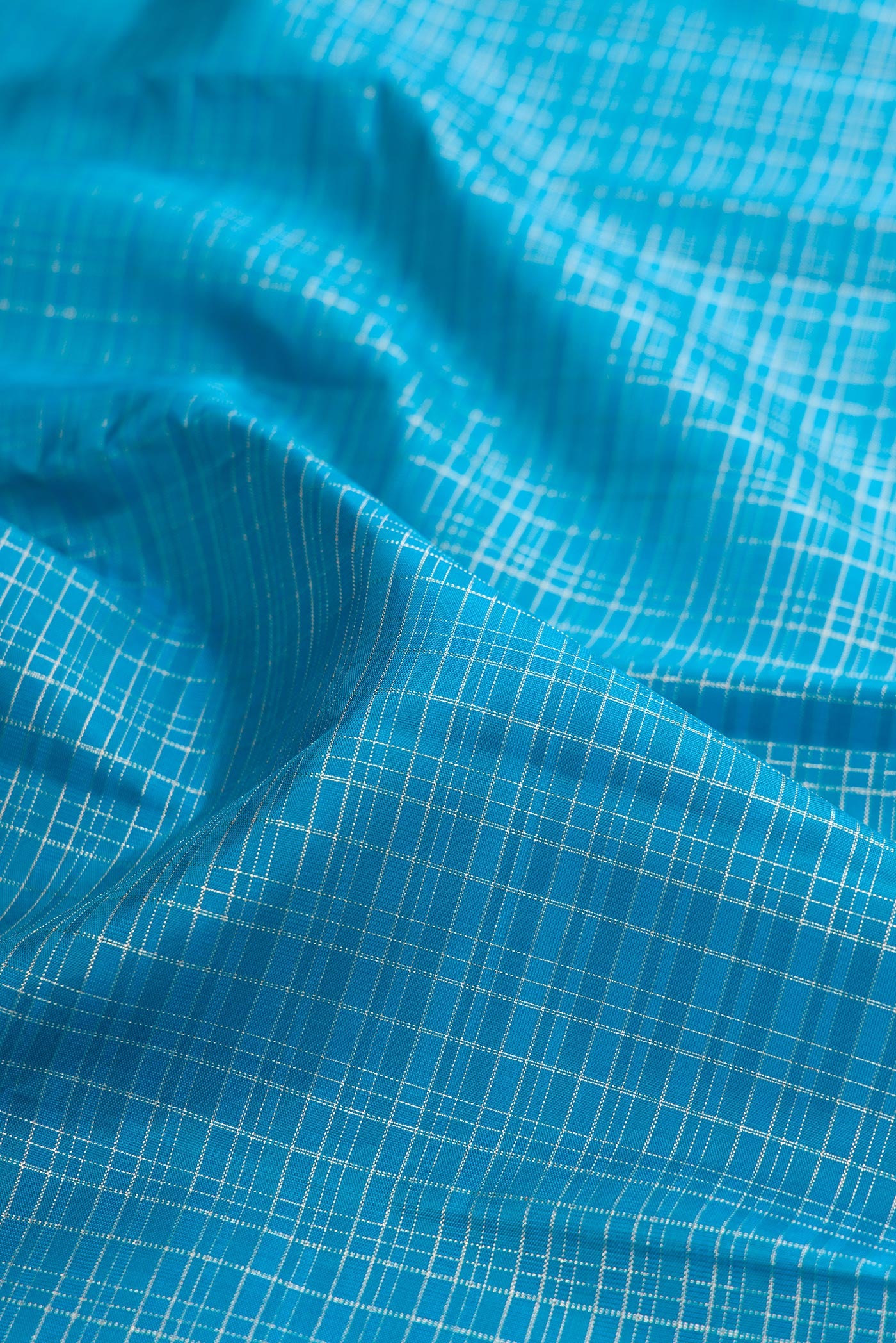 Close up of Sky Blue Kanchipuram Silk Saree with Checked design on the body and Zari Border.  displaying folds