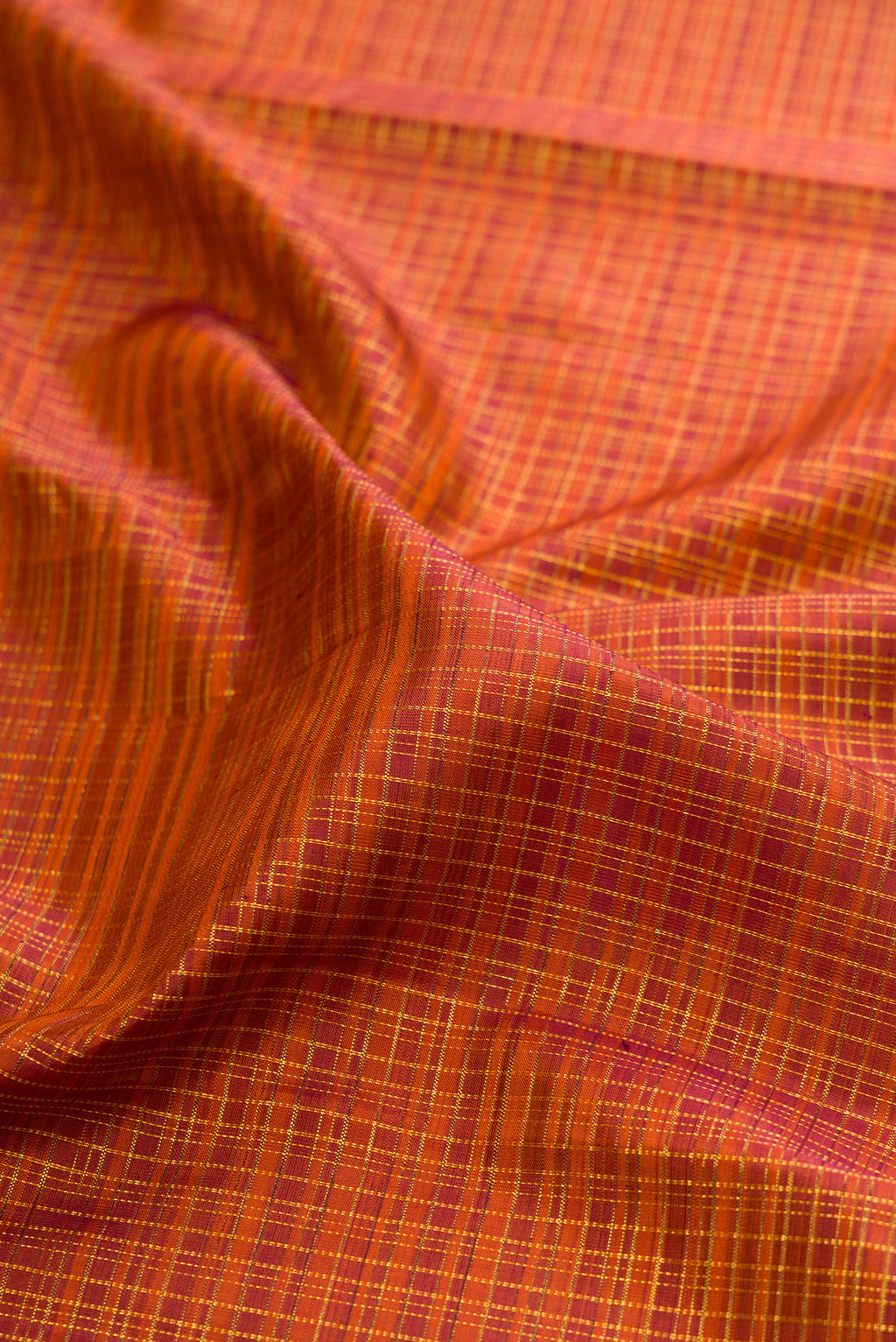 Close up of Brick Orange Kanchipuram Silk Saree with Checked design on the body and Zari Border.  displaying folds