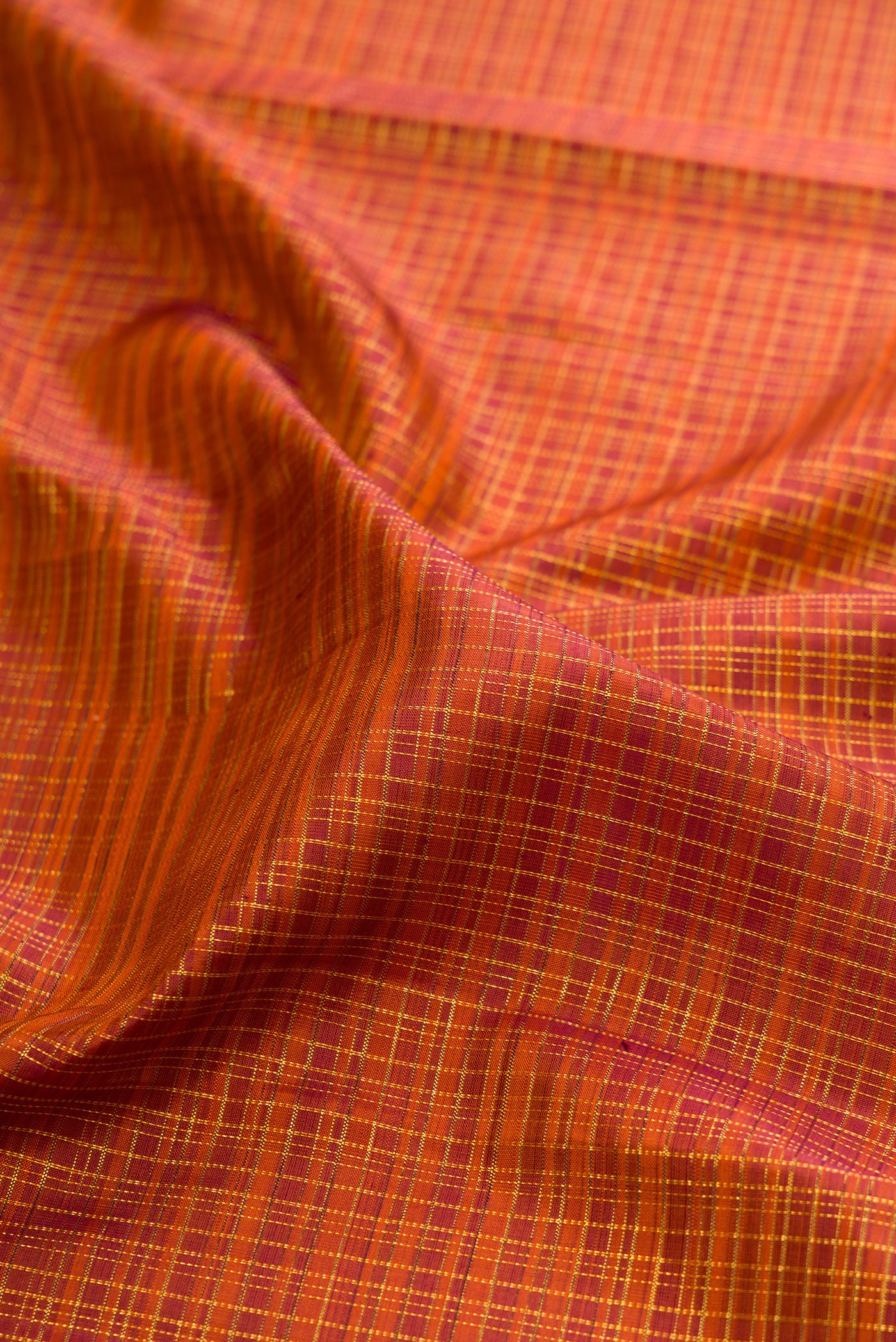 Close up of Brick Orange Kanchipuram Silk Saree with Checked design on the body and Zari Border.  displaying folds