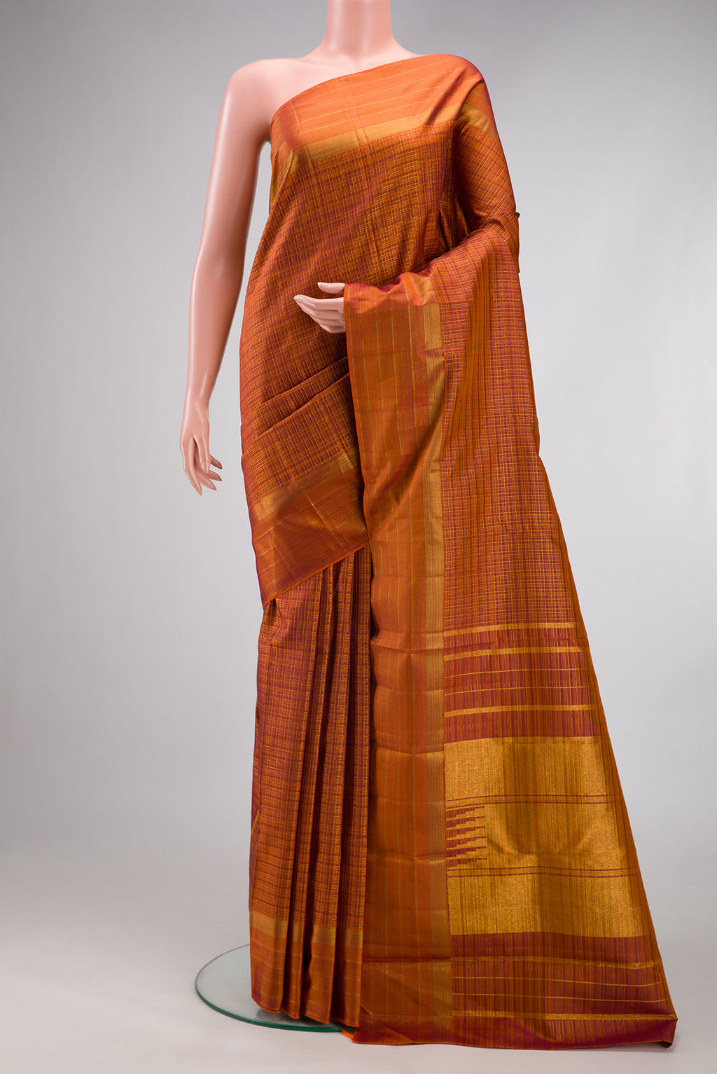 Brick Orange Kanchipuram Silk Saree with Checked design on the body and Zari Border.  displayed on a mannequin