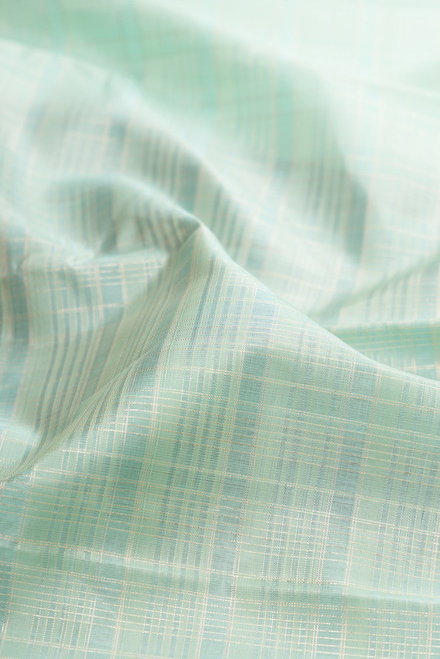 Close up of Mint Green Kanjivaram Silk Saree with Checked design on the body and Zari Border.  displaying folds