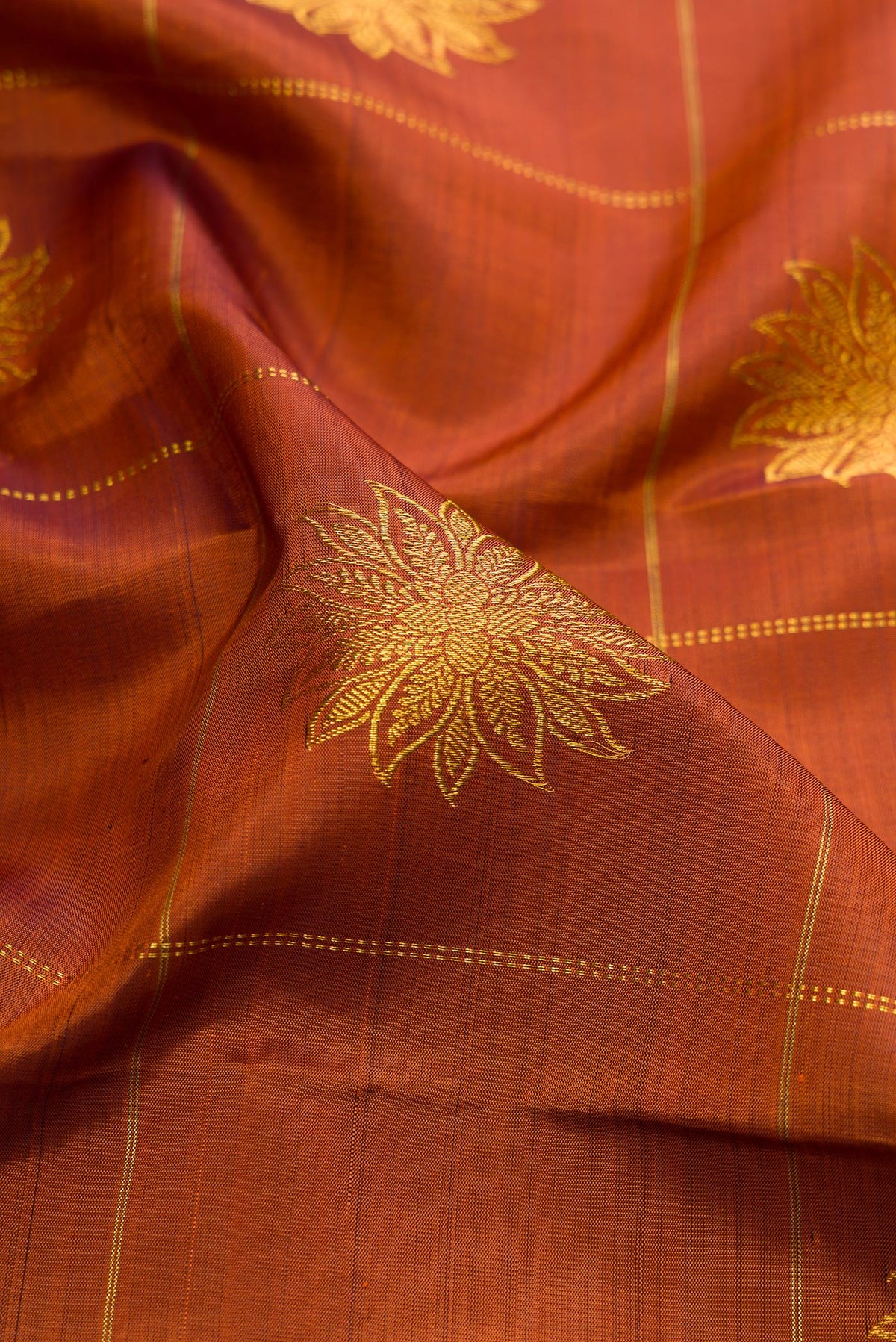 Close up of Rust Kanjivaram Silk Saree with Checked design on the body and Zari Border.  displaying folds