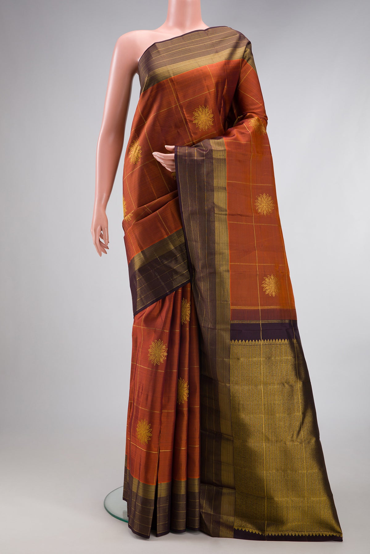 Rust Kanjivaram Silk Saree with Checked design on the body and Zari Border.  displayed on a mannequin