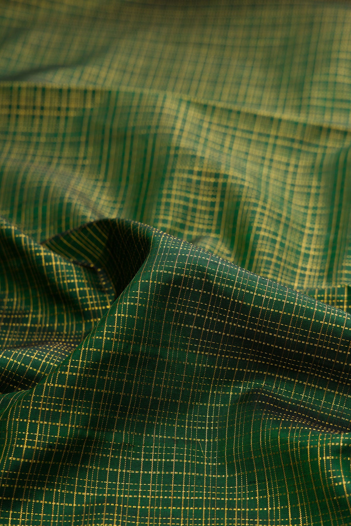 Close up of Bottle Green Kanjivaram Silk Saree with Checked design on the body and Zari Border.  displaying folds