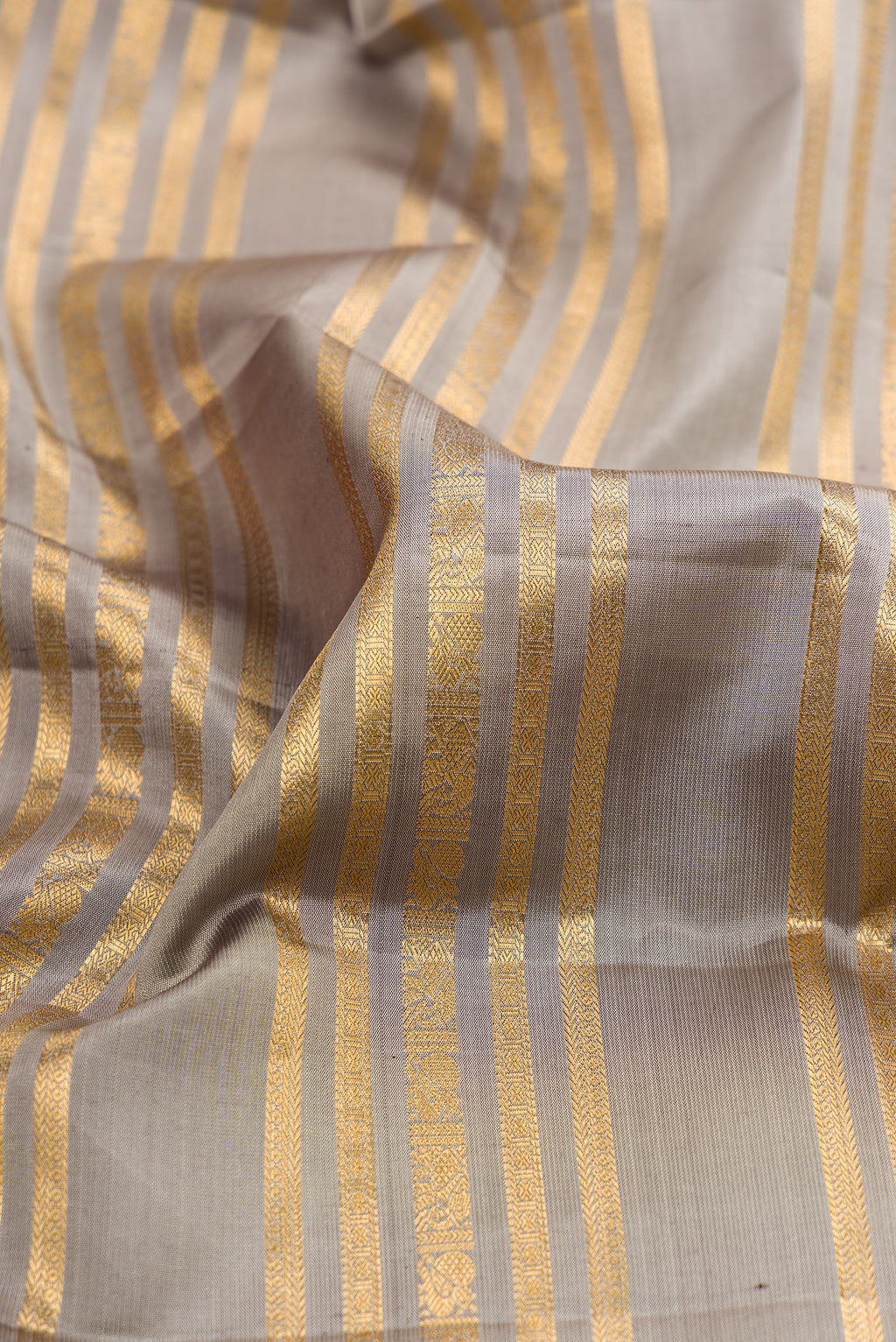 Close up of Grey Kanjivaram Silk Saree with Stripes on the body and Zari Border.  displaying folds