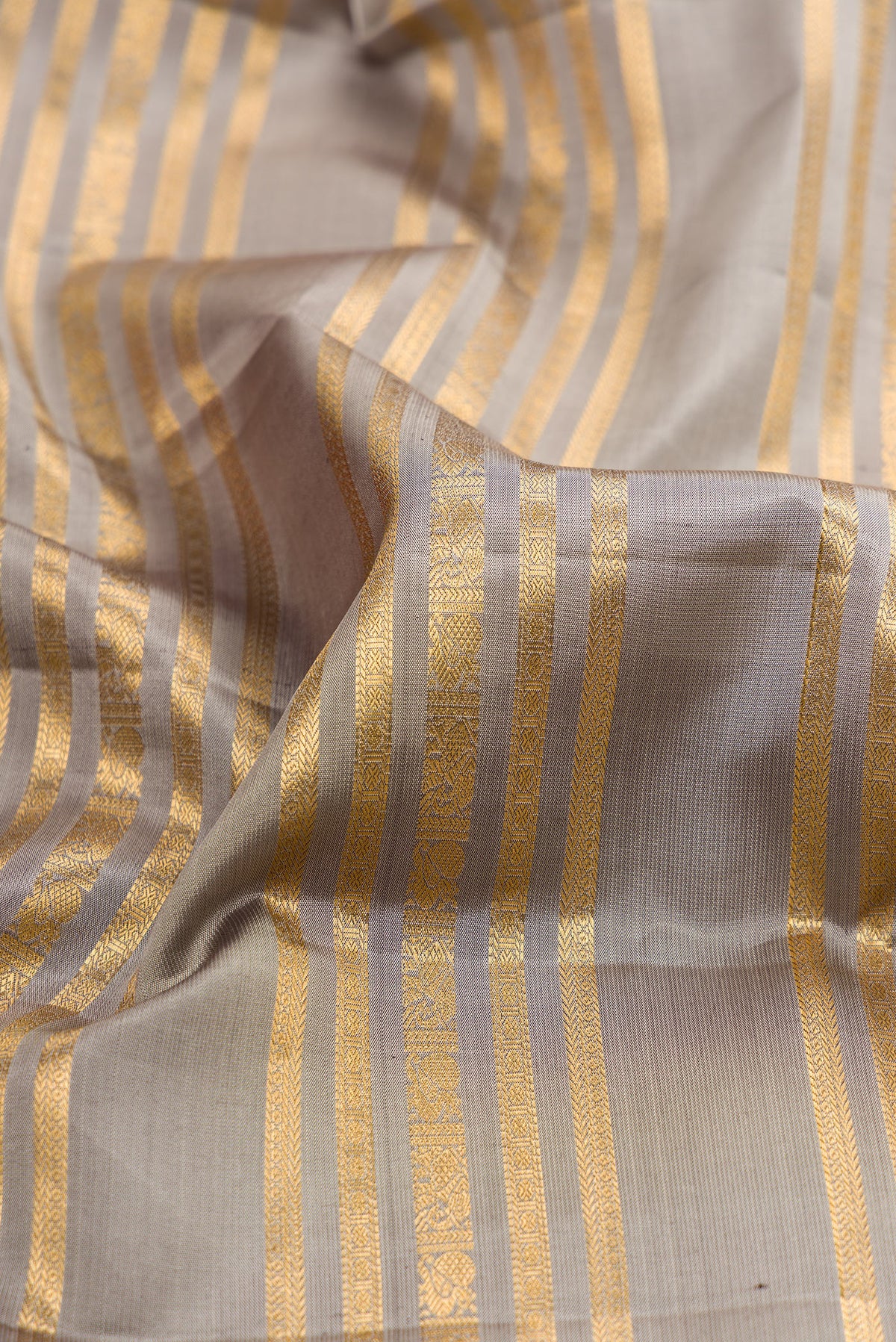 Close up of Grey Kanjivaram Silk Saree with Stripes on the body and Zari Border.  displaying folds