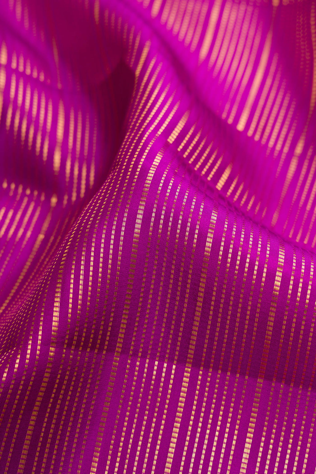Close up of Magenta Kanjivaram Silk Saree with Stripes on the body and Fancy Border.  displaying folds