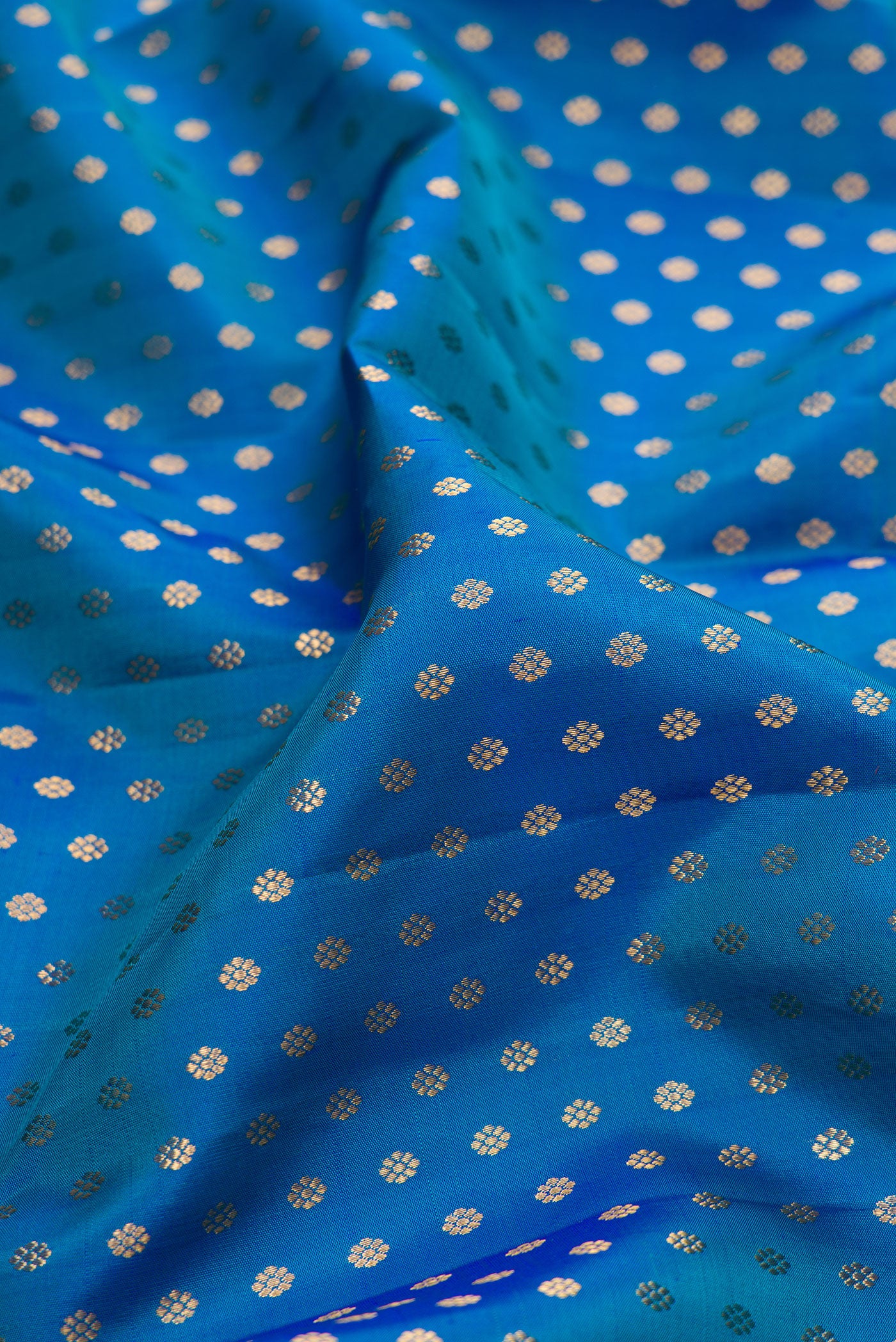 Close up of Peacock Blue Kanjivaram Silk Saree with Zari Butta on the body and Zari Border.  displaying folds
