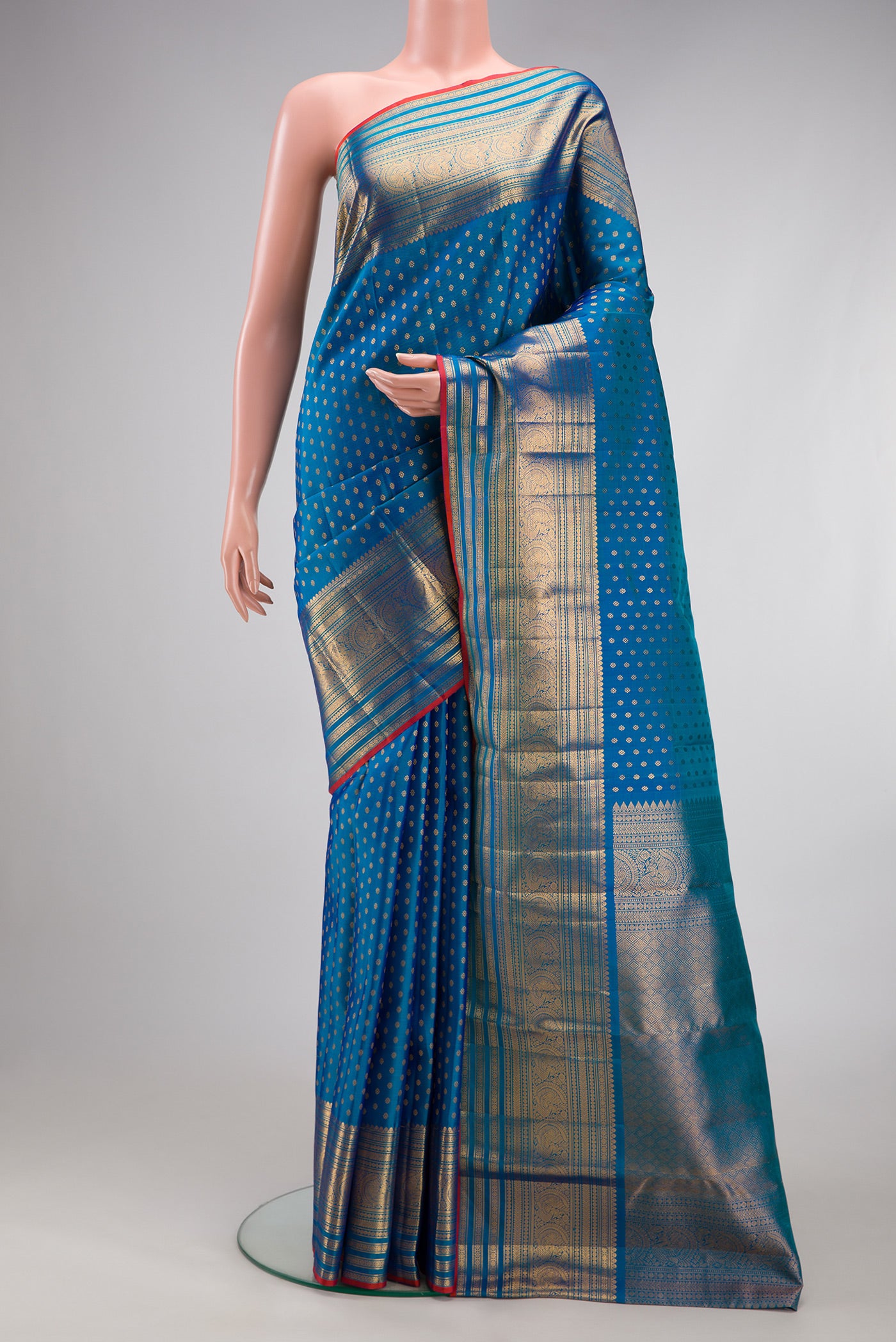 Peacock Blue Kanjivaram Silk Saree with Zari Butta on the body and Zari Border.  displayed on a mannequin