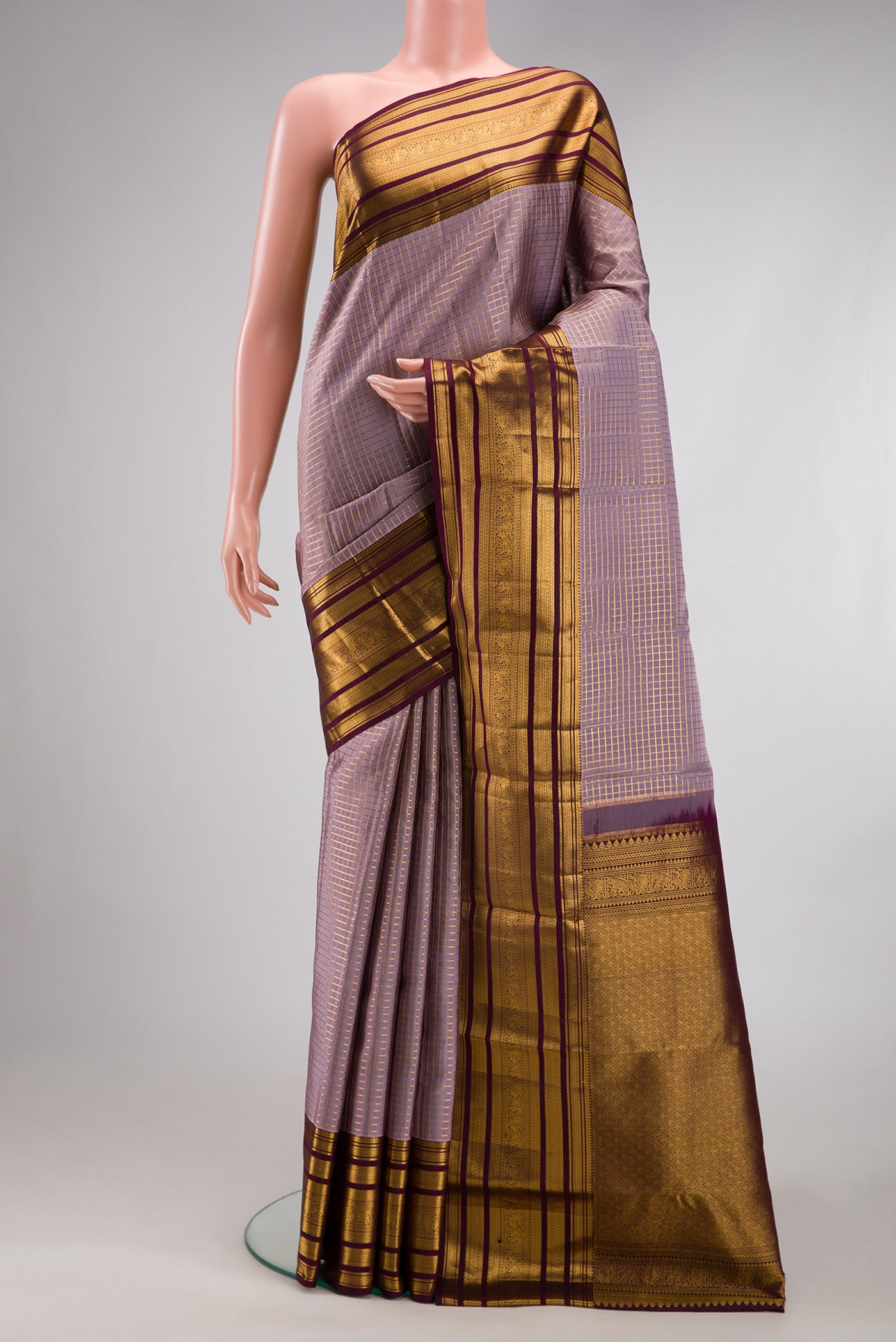 Lilac Kanjivaram Silk Saree with Checked design on the body and Zari Border.  displayed on a mannequin