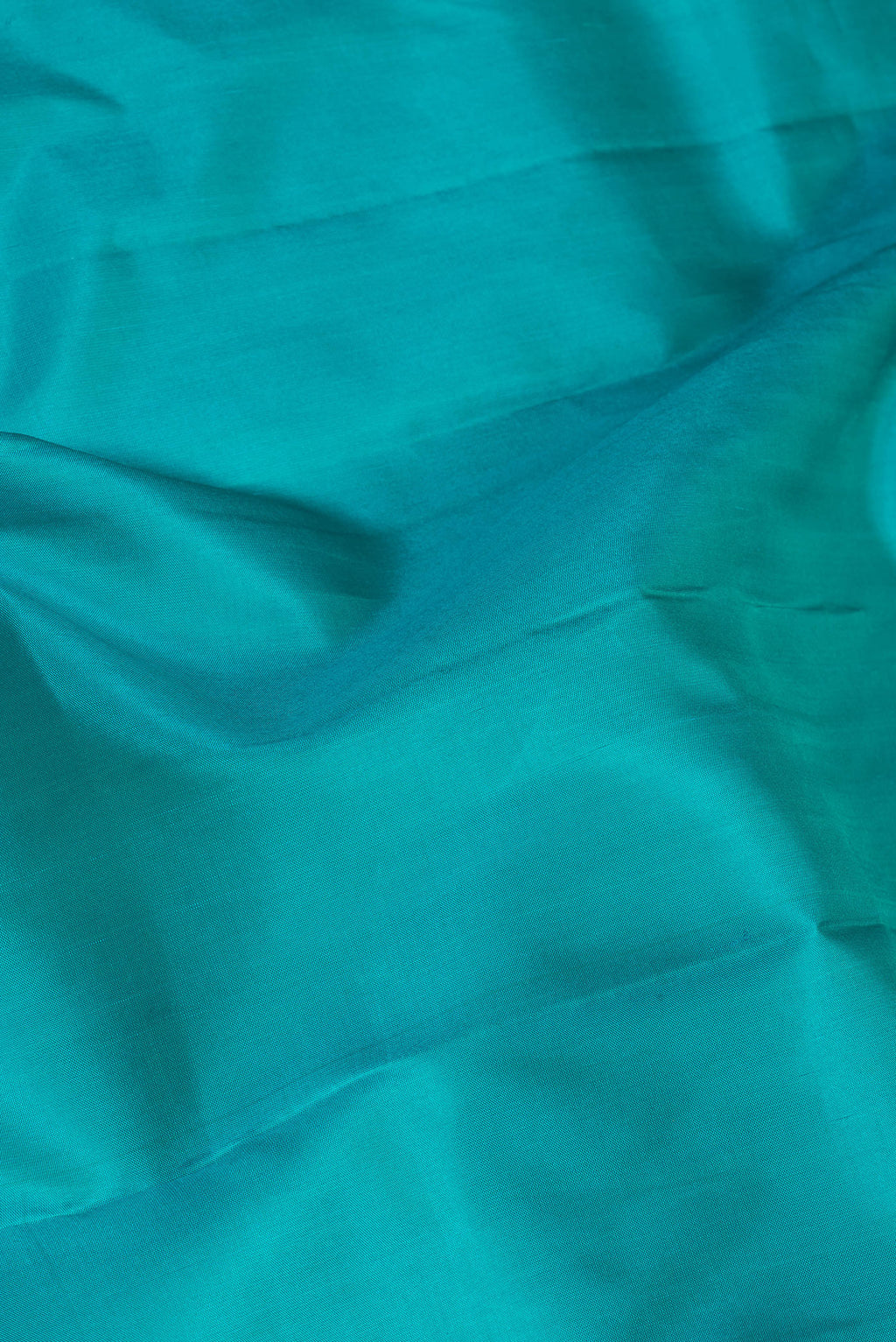 Close up of Peacock Blue Kanjivaram Silk Saree with Plain Body and Zari Border.  displaying folds