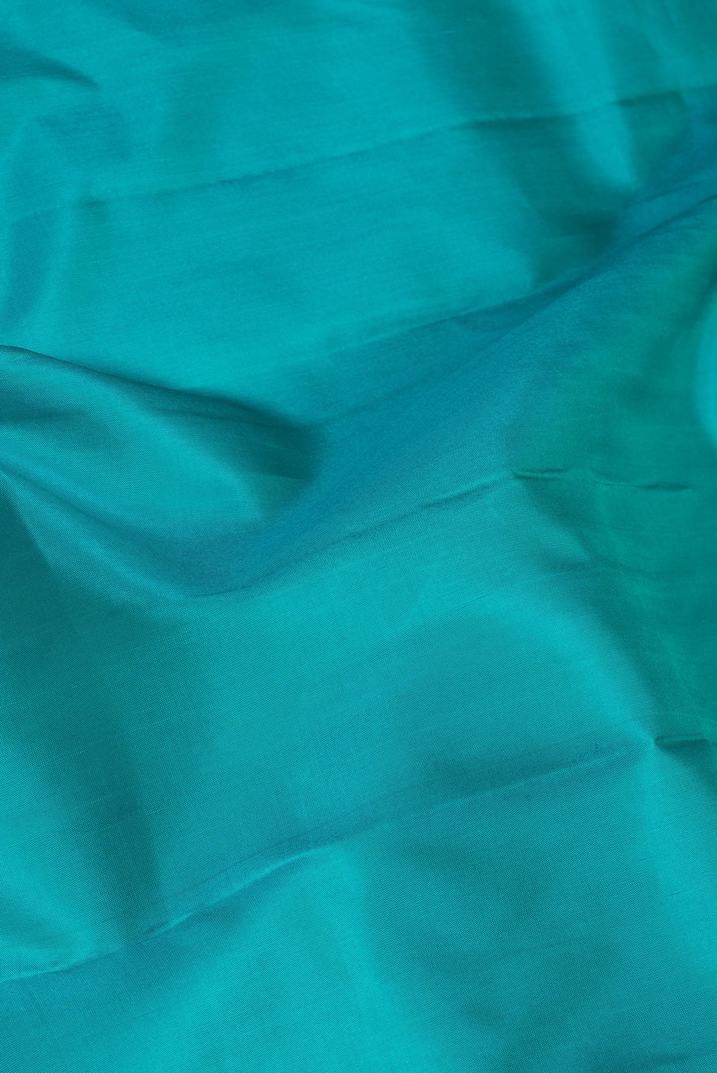 Close up of Peacock Blue Kanjivaram Silk Saree with Plain Body and Zari Border.  displaying folds
