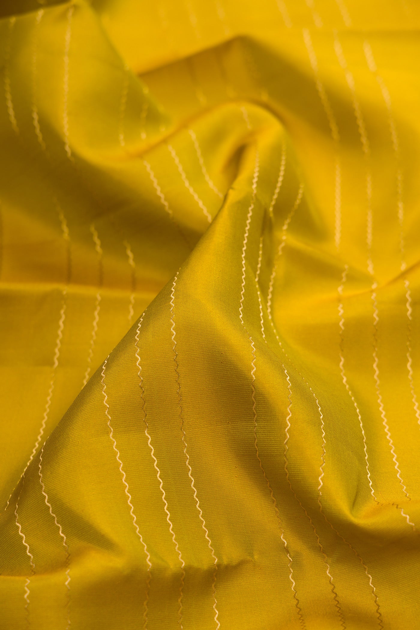 Close up of Mehandi Green Kanchipuram Silk Saree with Veldhari on the body and Zari Border.  displaying folds