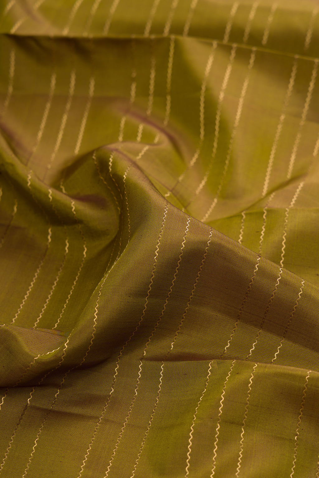 Close up of Mehandi Green Kanchipuram Silk Saree with Veldhari on the body and Zari Border.  displaying folds